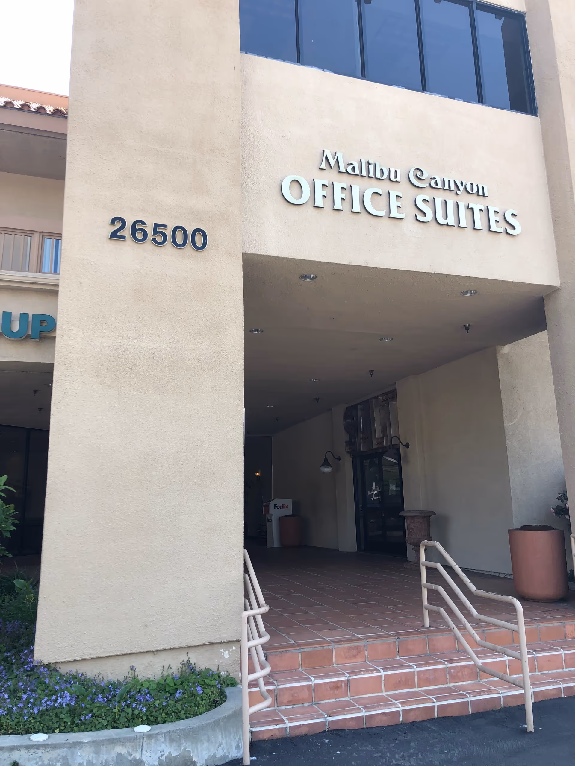 Beige building entrance with Malibu Canyon Office Suites sign, address 26500, and accessible ramp.