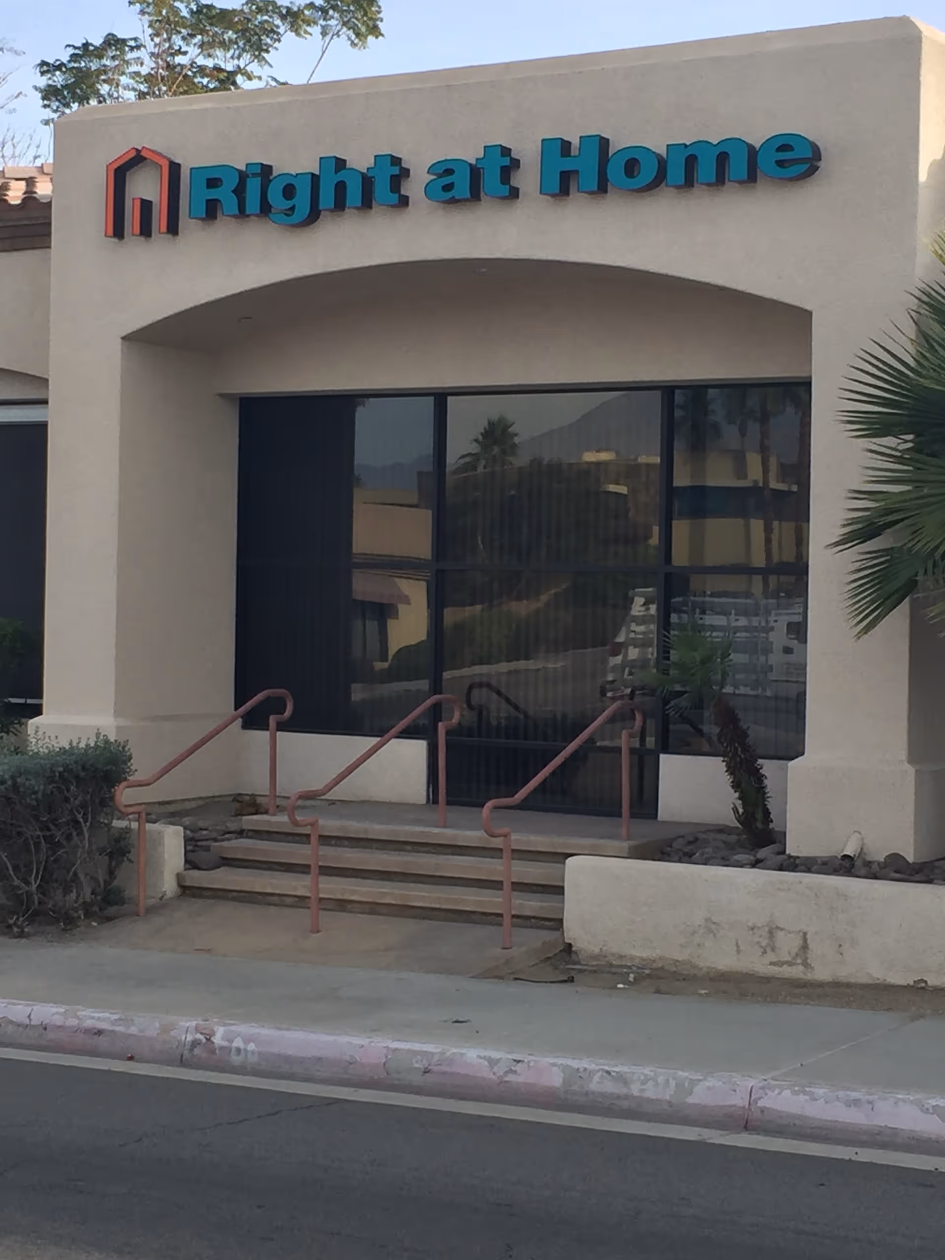 Front exterior of Right at Home facility with stairs and a large sign.