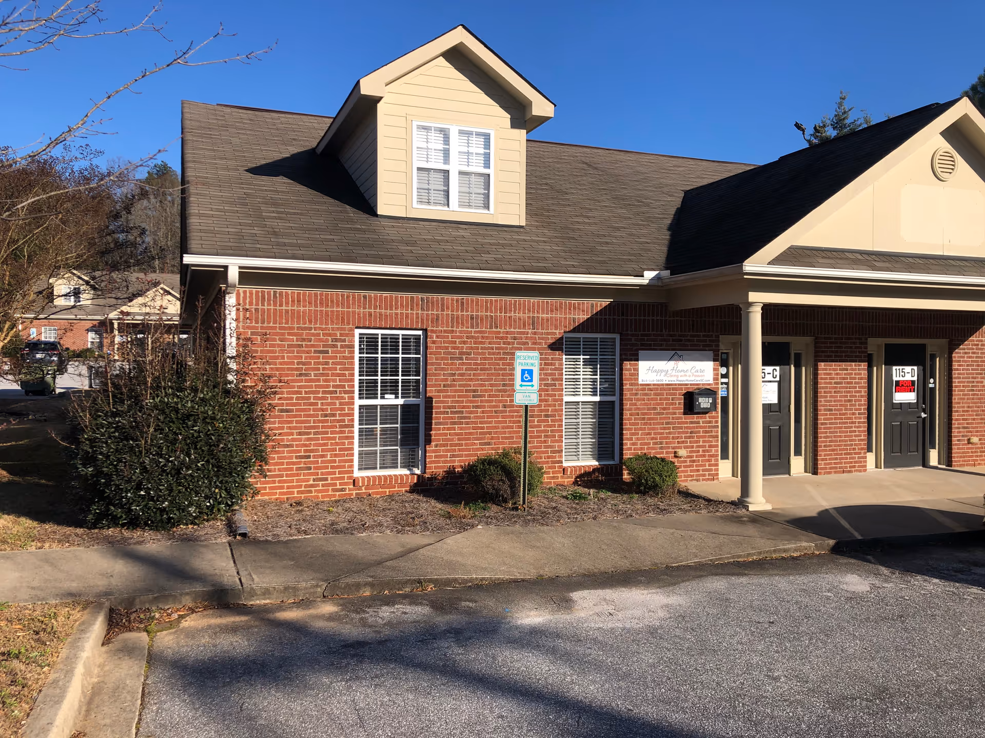 Brick exterior of Happy Home Care facility with entrance, sign, and parking.