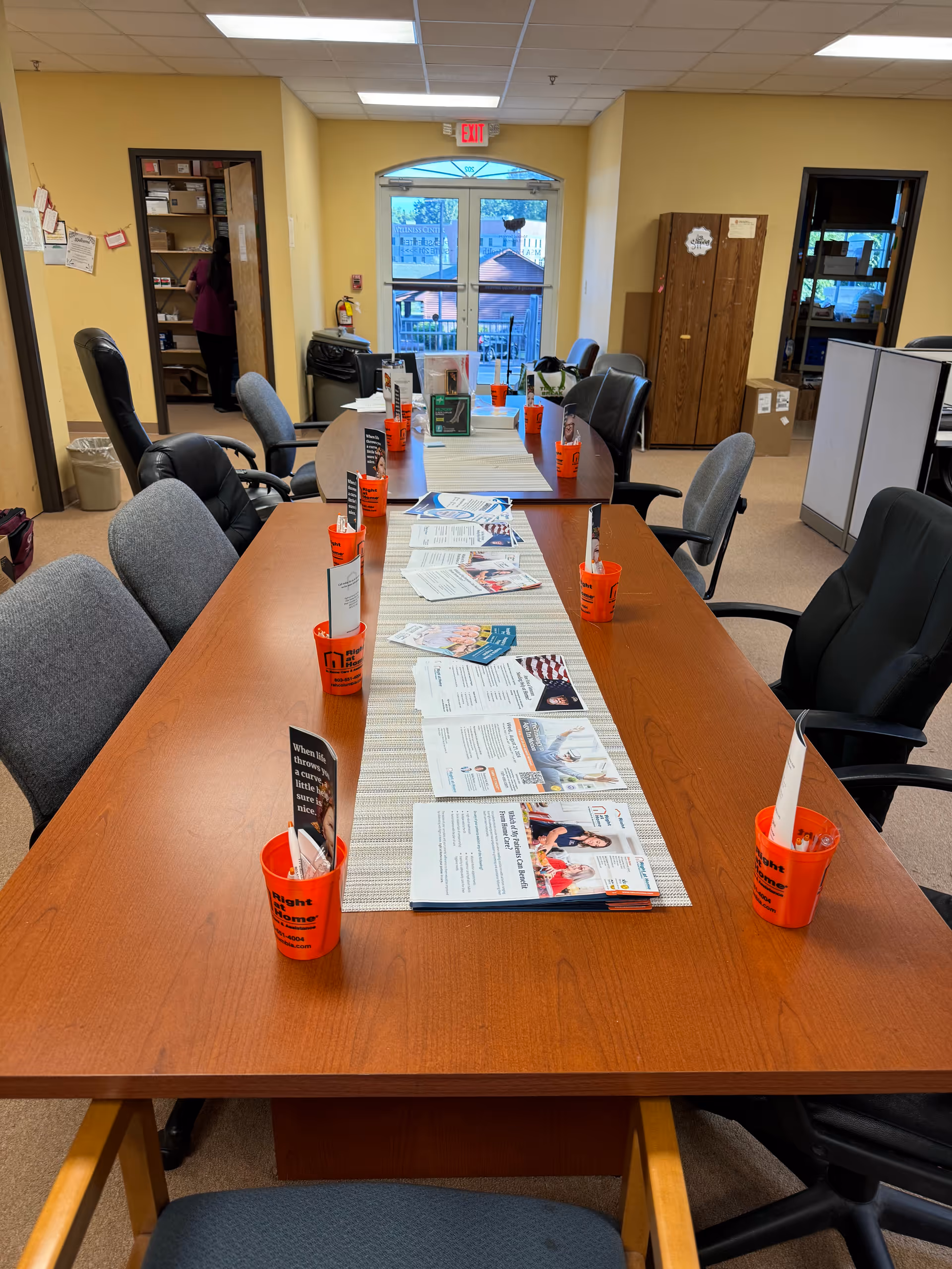 Long wooden conference table with papers and orange cups in a senior living facility common area.
