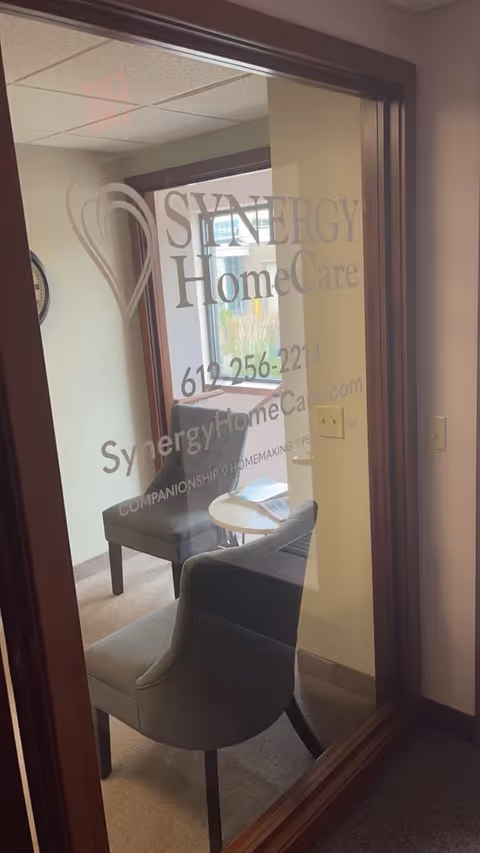 Glass door shows the Synergy HomeCare logo and a small interior seating area.