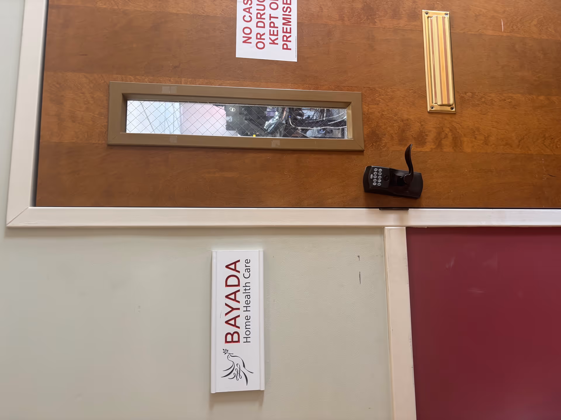 Wooden door with a small window, keypad lock, and BAYADA Home Health Care sign.