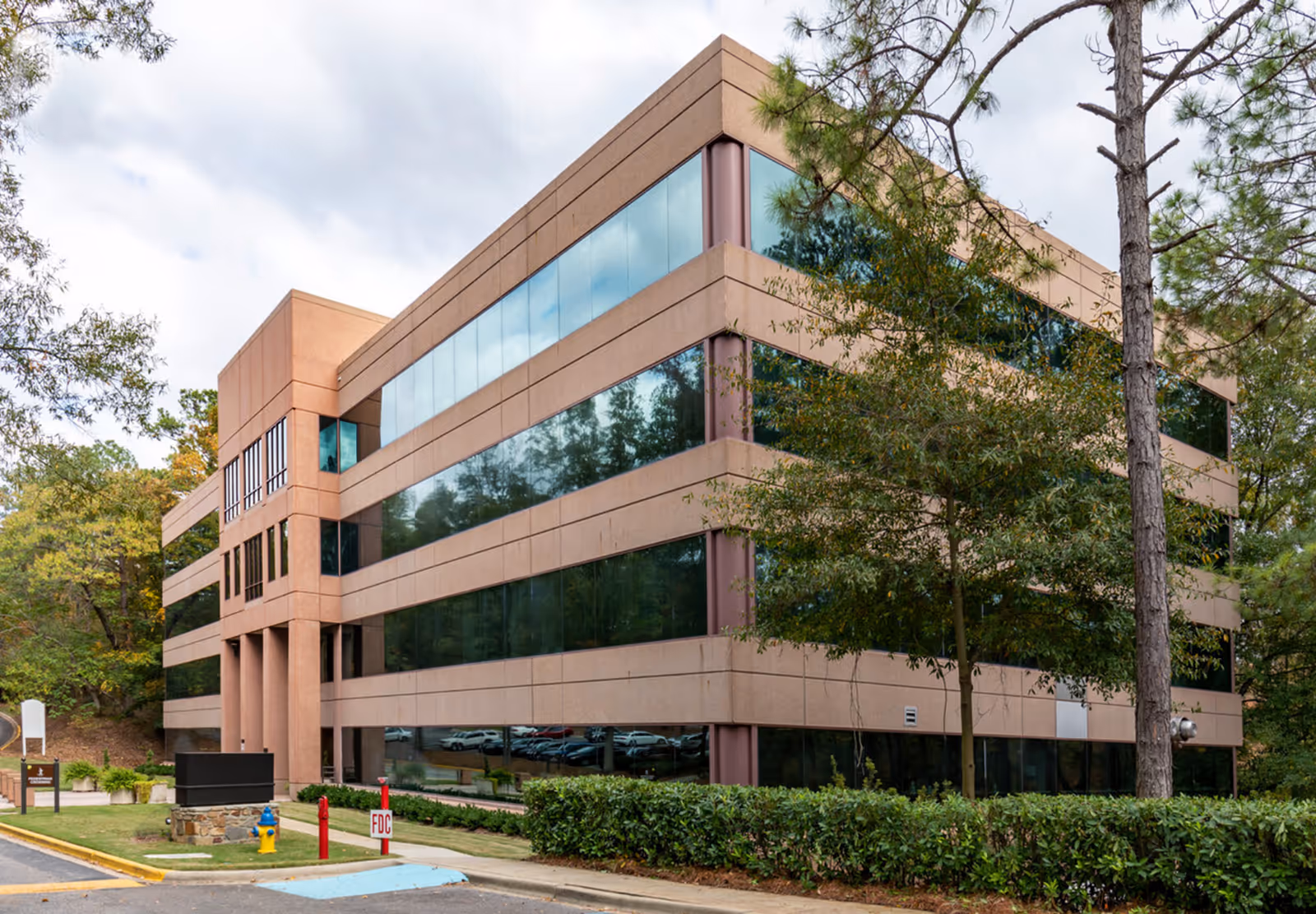 A modern, multi-story Compassus facility exterior with large glass windows and trees.