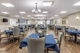 Spacious dining hall with blue tablecloths, chairs, and floral centerpieces.