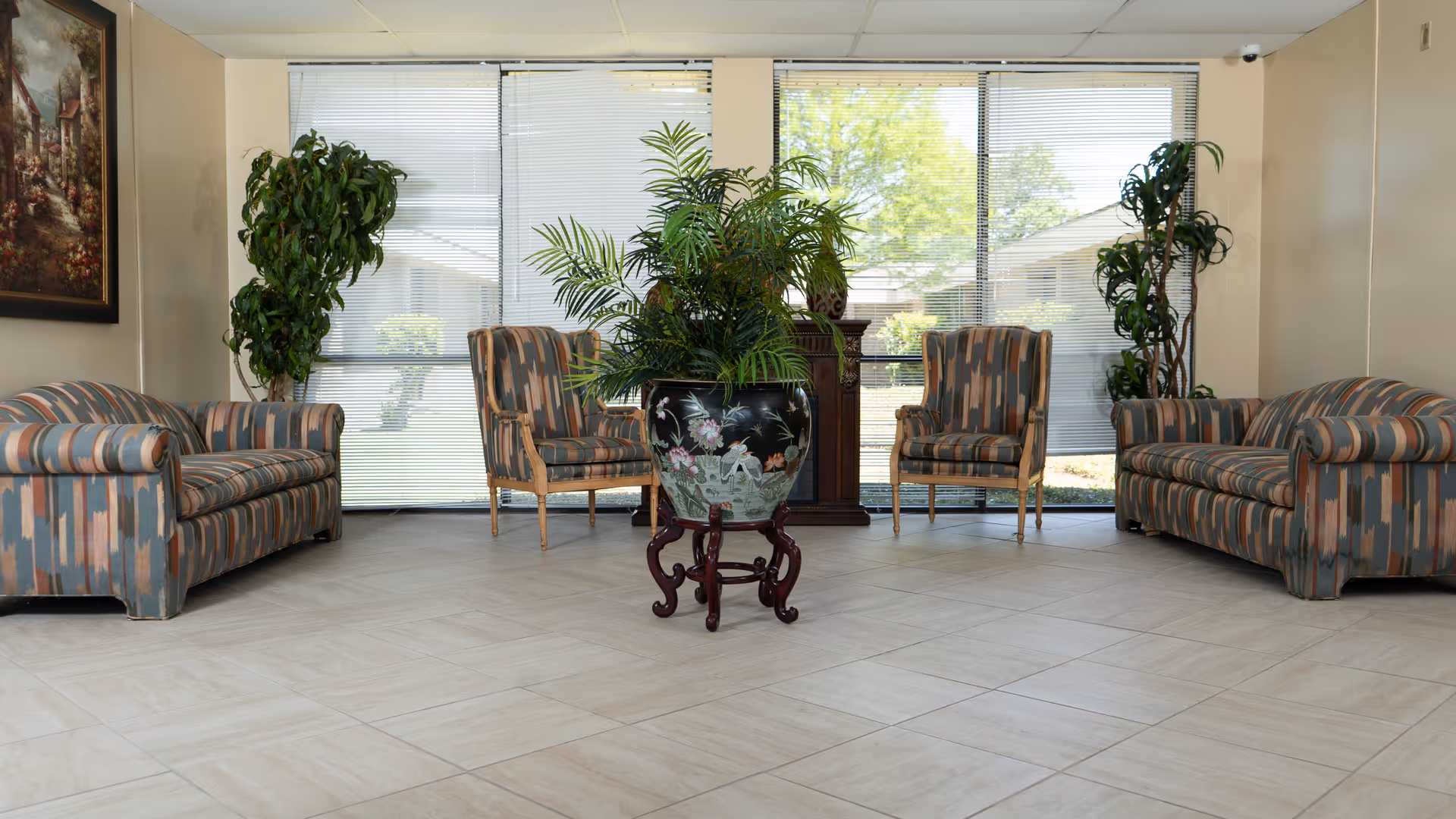 Bright indoor waiting area with striped couches, chairs, and large plants.
