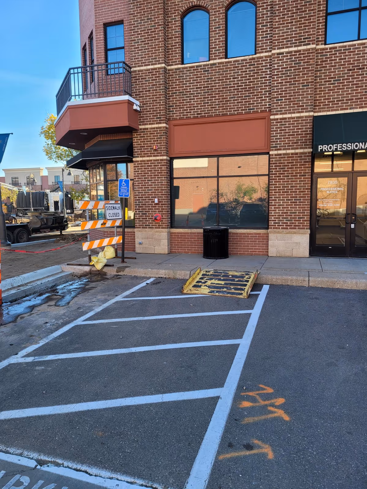 Brick building exterior with large storefront windows, sidewalk, and a handicapped parking sign.