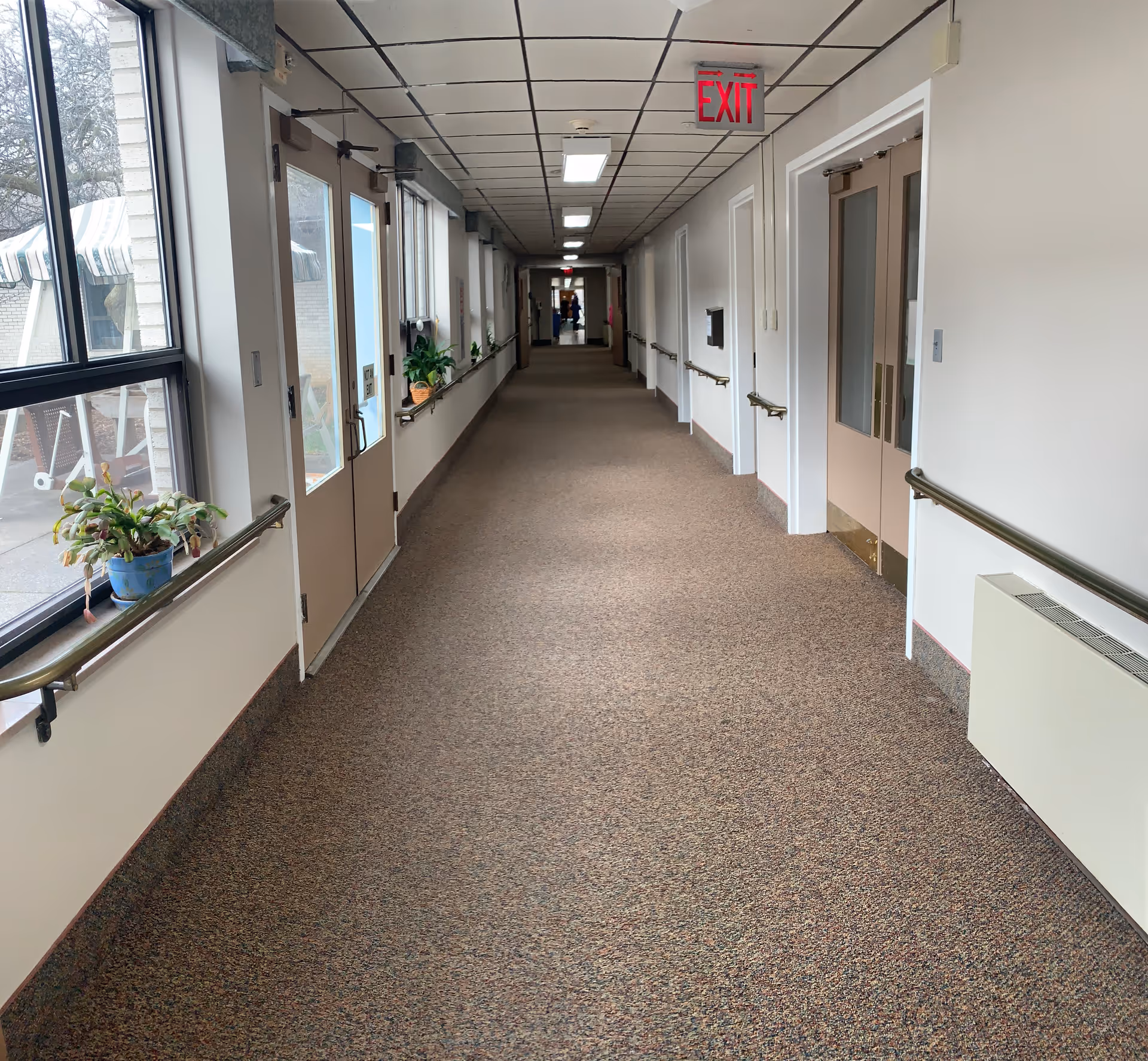 Long interior corridor of a senior living facility with doors and windows.