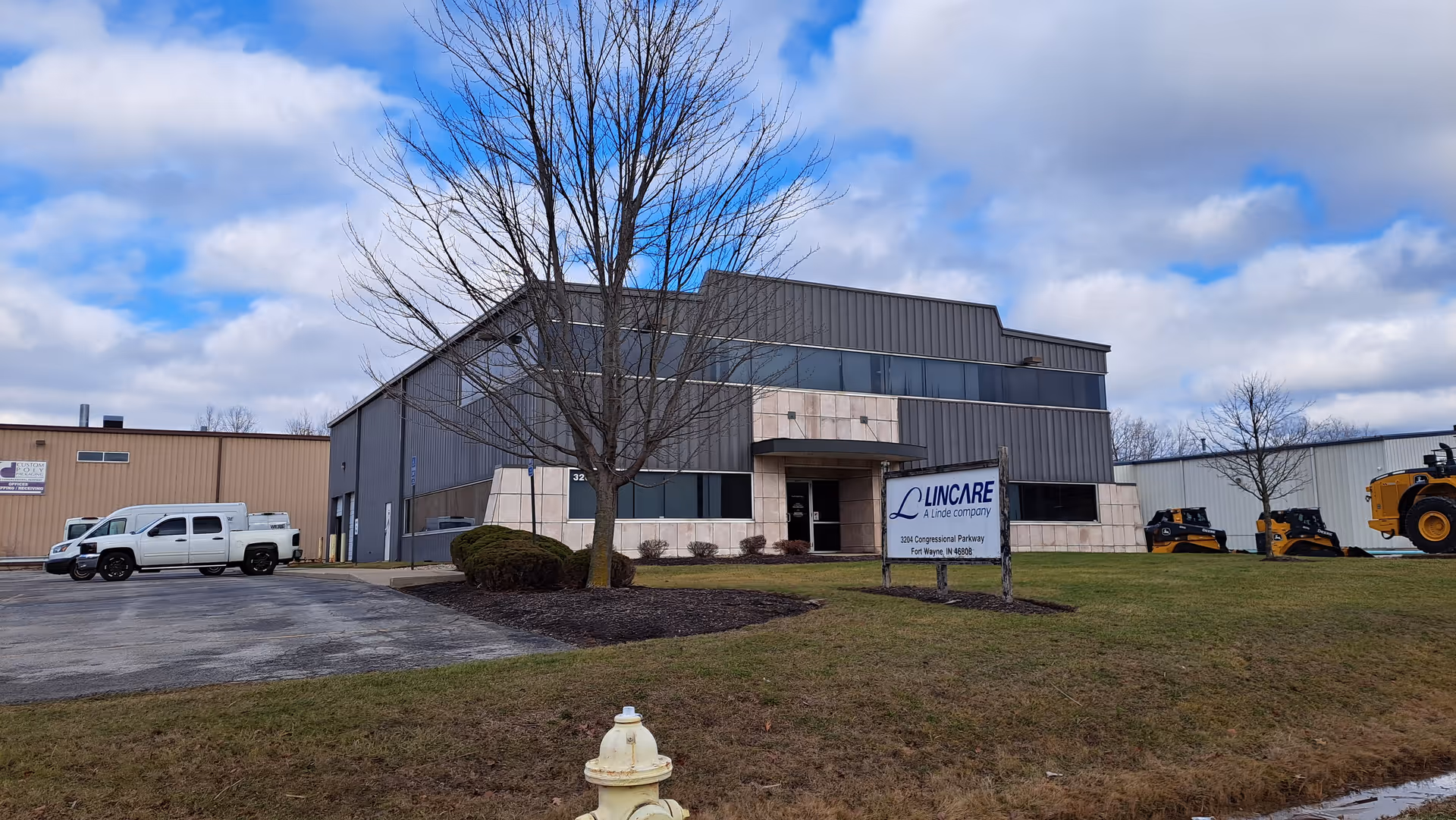 Exterior view of a LINCARE facility with a sign, parking lot, and blue sky.