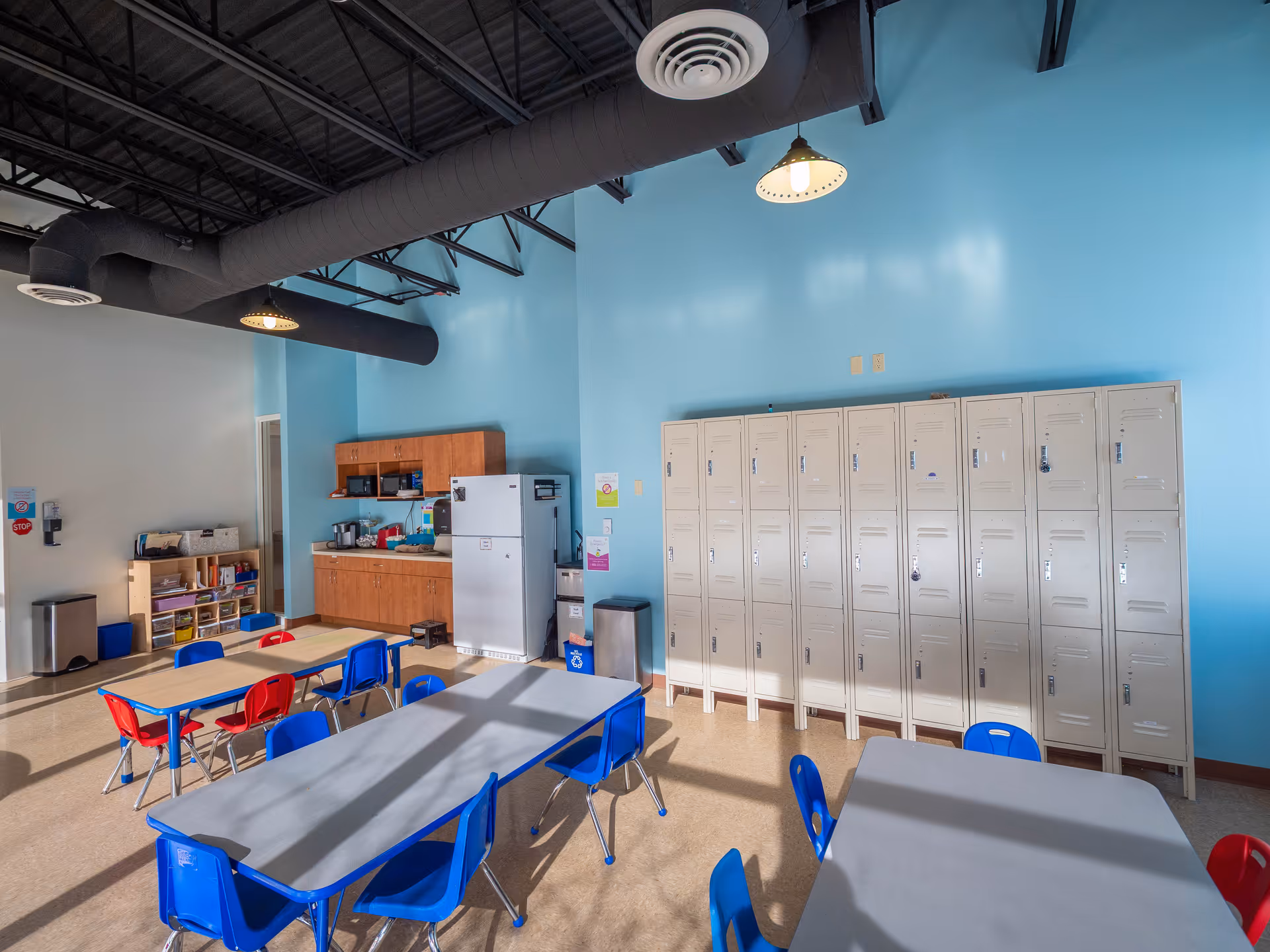 Bright blue-walled classroom in WEAP facility with lockers and tables.