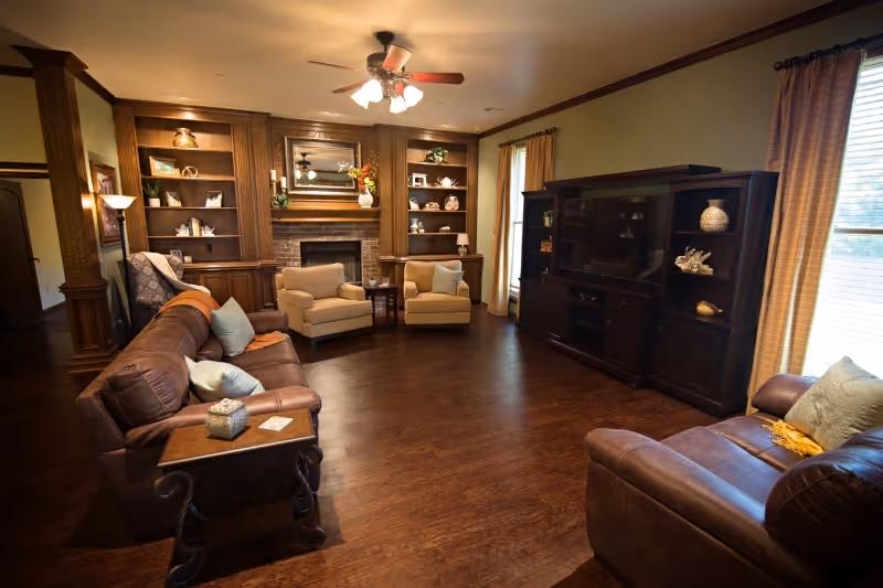 Cozy living room with leather sofas, built-in bookshelves, and a fireplace.