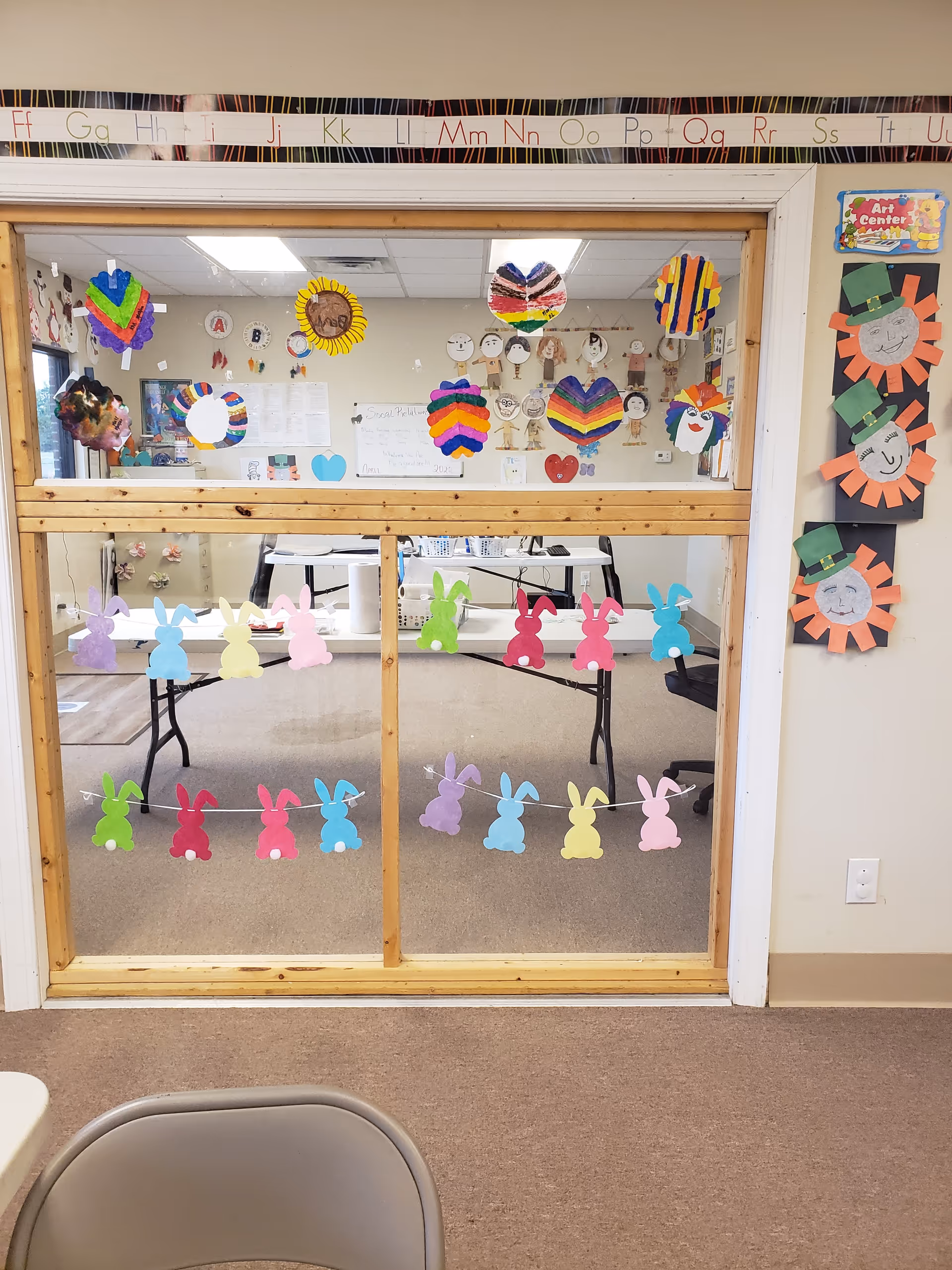 Glass partition decorated with colorful bunny crafts and artwork in a craft room.