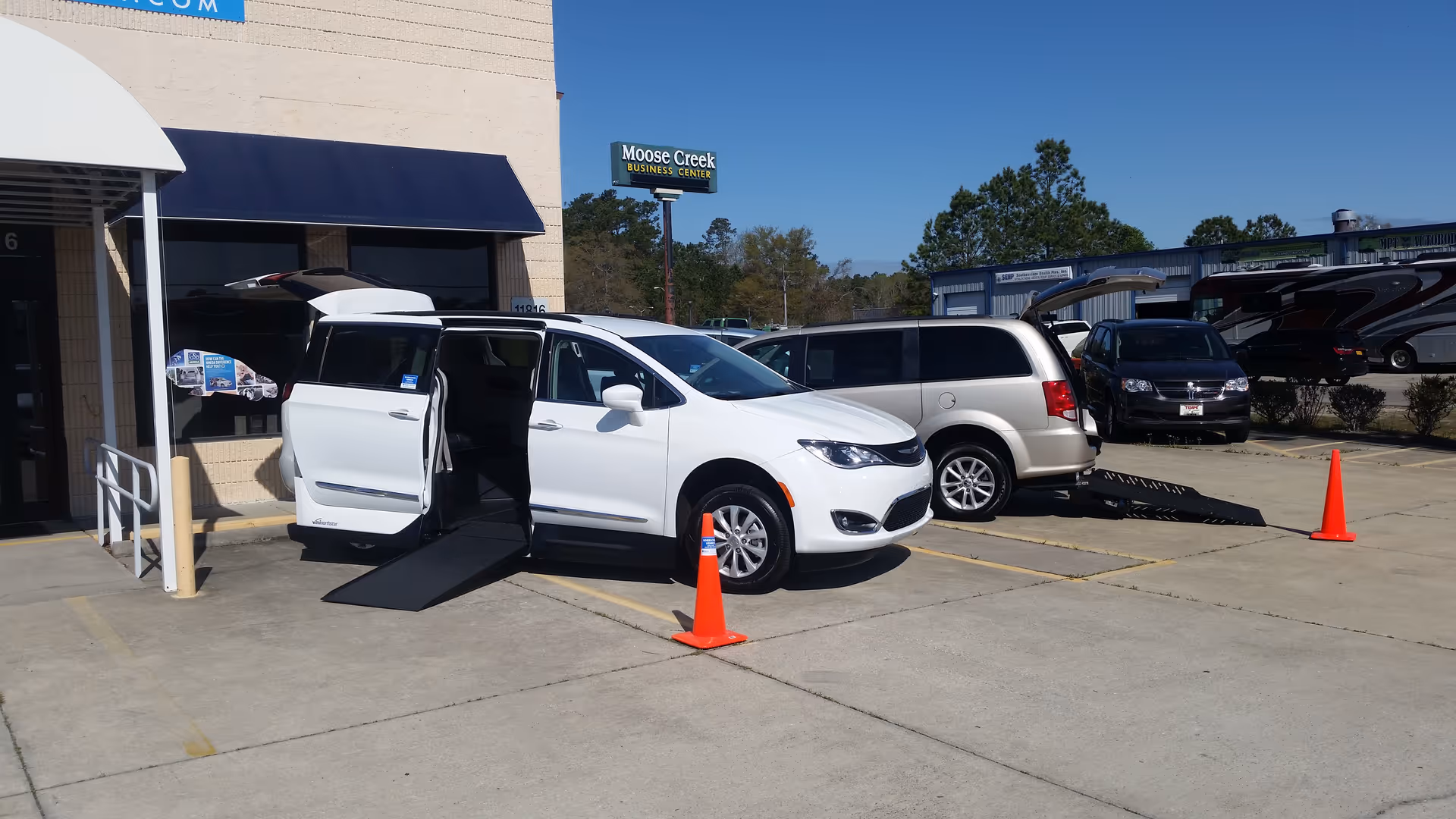 White wheelchair van with ramp extended in a parking lot outside MobilityWorks.