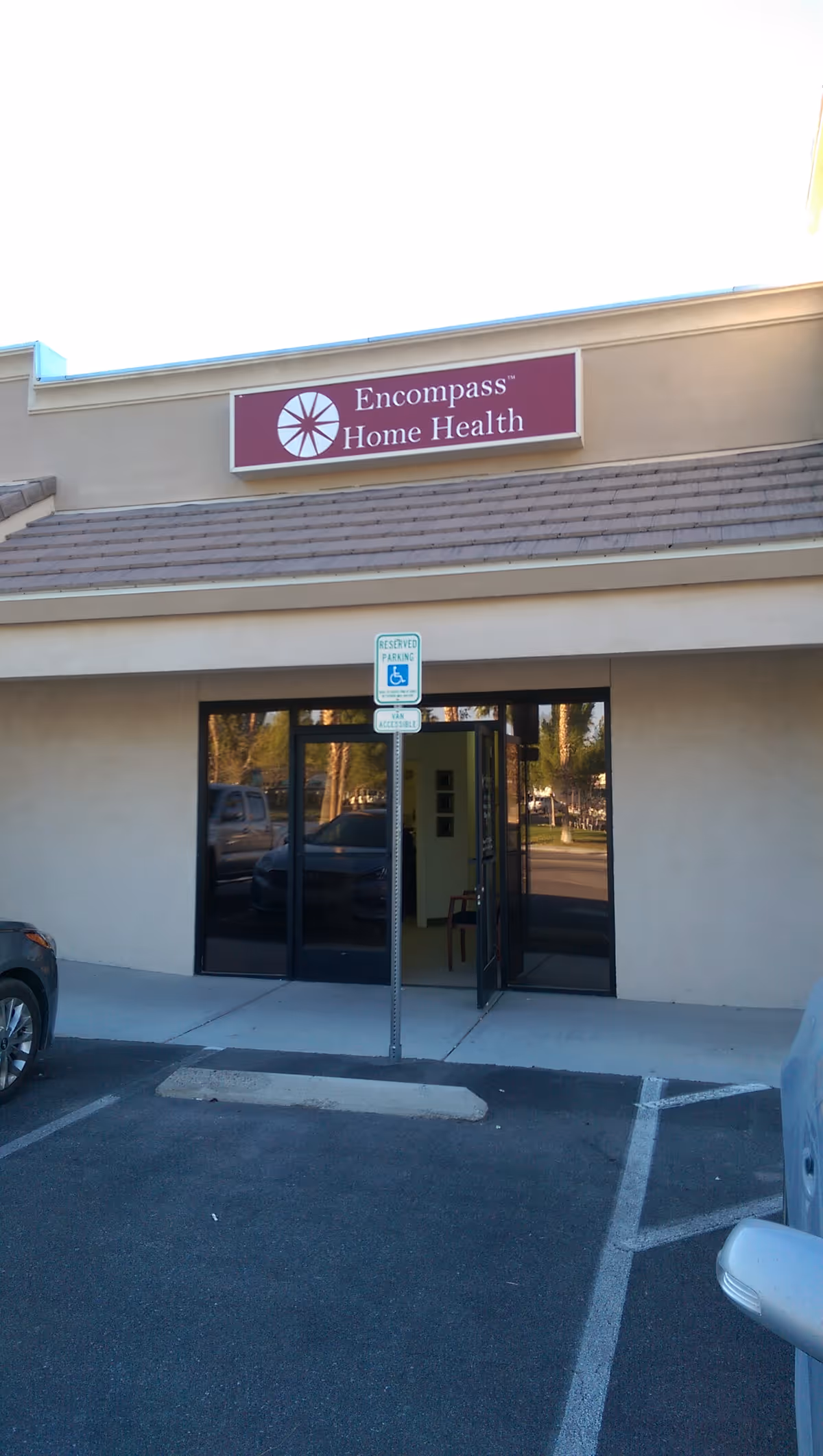 Front view of building entrance with Encompass Home Health sign and parking