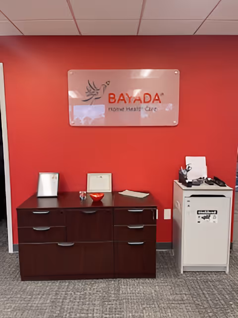Red-walled reception area with BAYADA sign above a dark wooden cabinet.