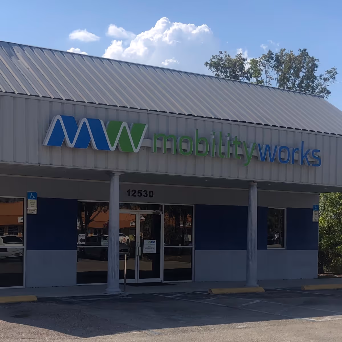 Front exterior of MobilityWorks facility with blue green logo signage and glass entrance.