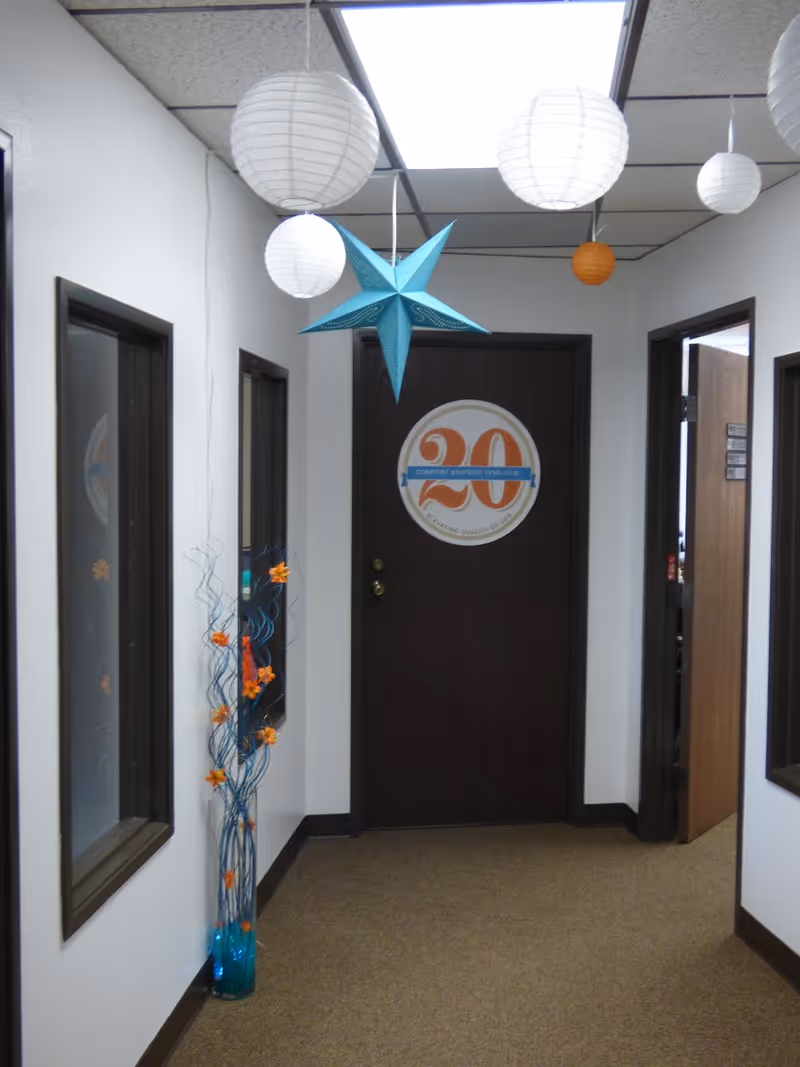 Indoor hallway of a senior care facility with hanging lanterns and a door logo