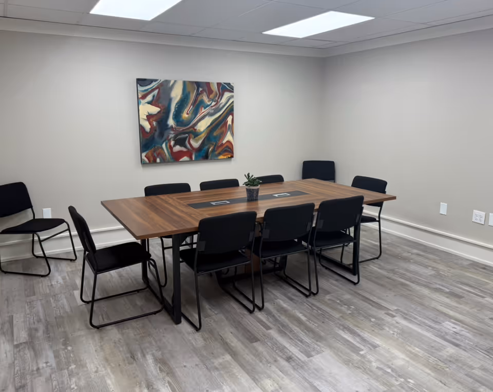 A modern dining room with a long wooden table and black chairs.