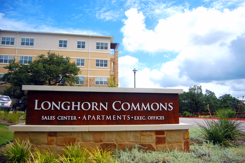 Exterior view of Longhorn Commons sign with a multi-story building behind.