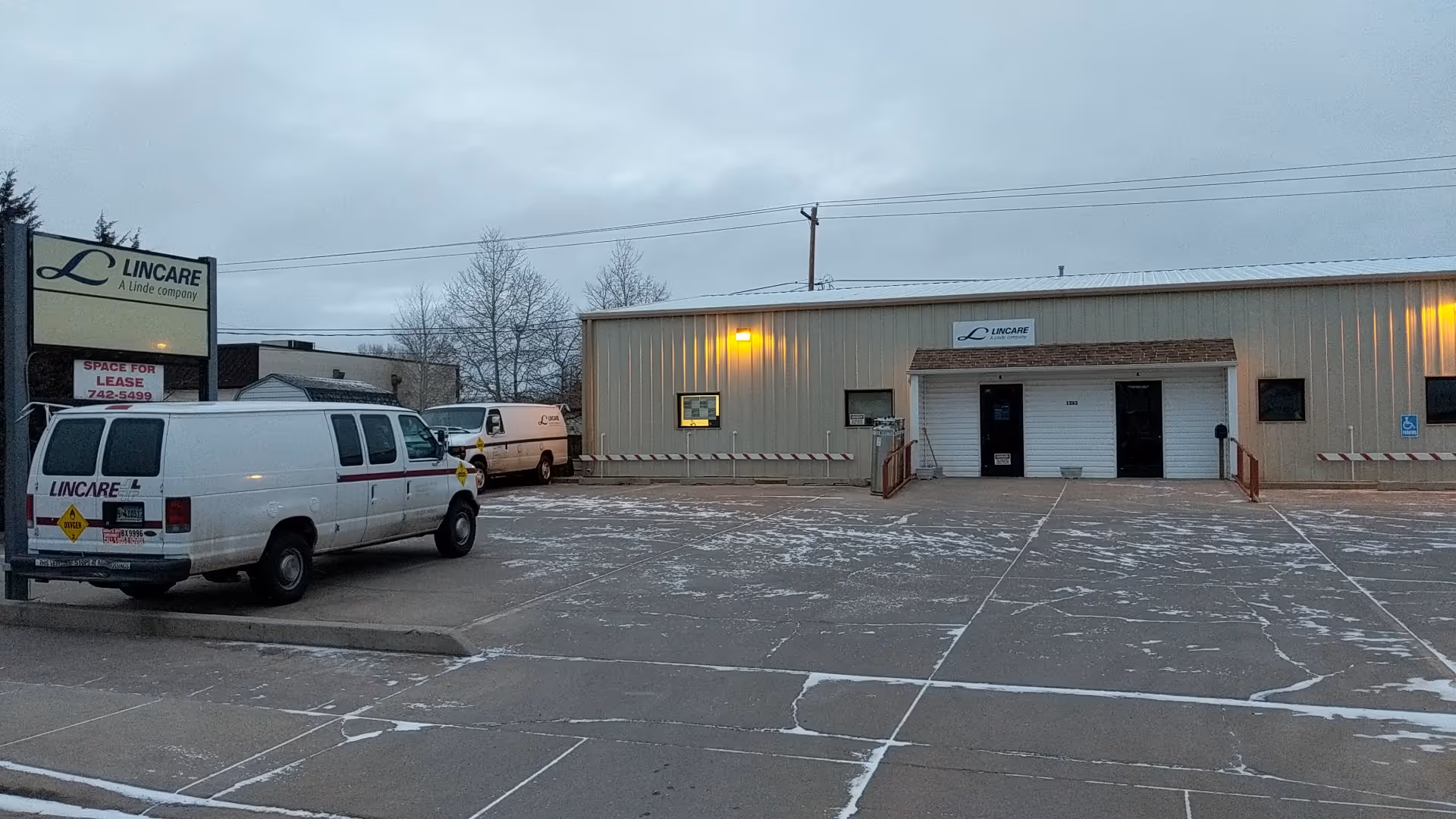 Exterior view of a LINCARE facility with a parking lot and white vans.