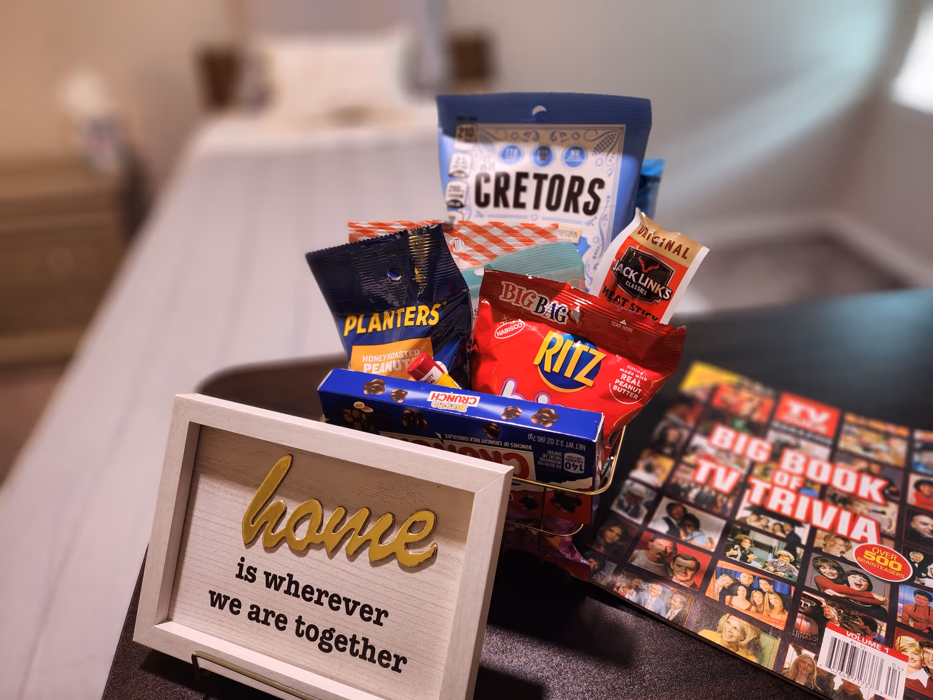 An assortment of snacks on a bedside table in a cozy bedroom.