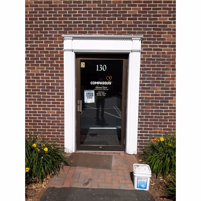 Brick building entrance with a glass door labeled Compassus and the number 130.