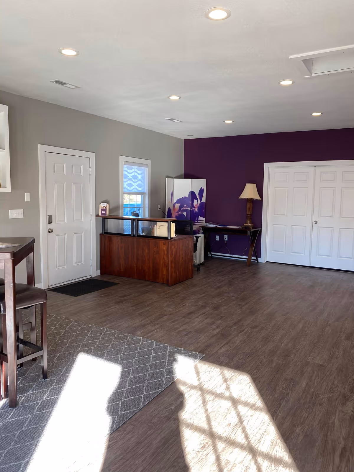 Reception area of a senior facility with a wooden desk, purple wall, and lamps.