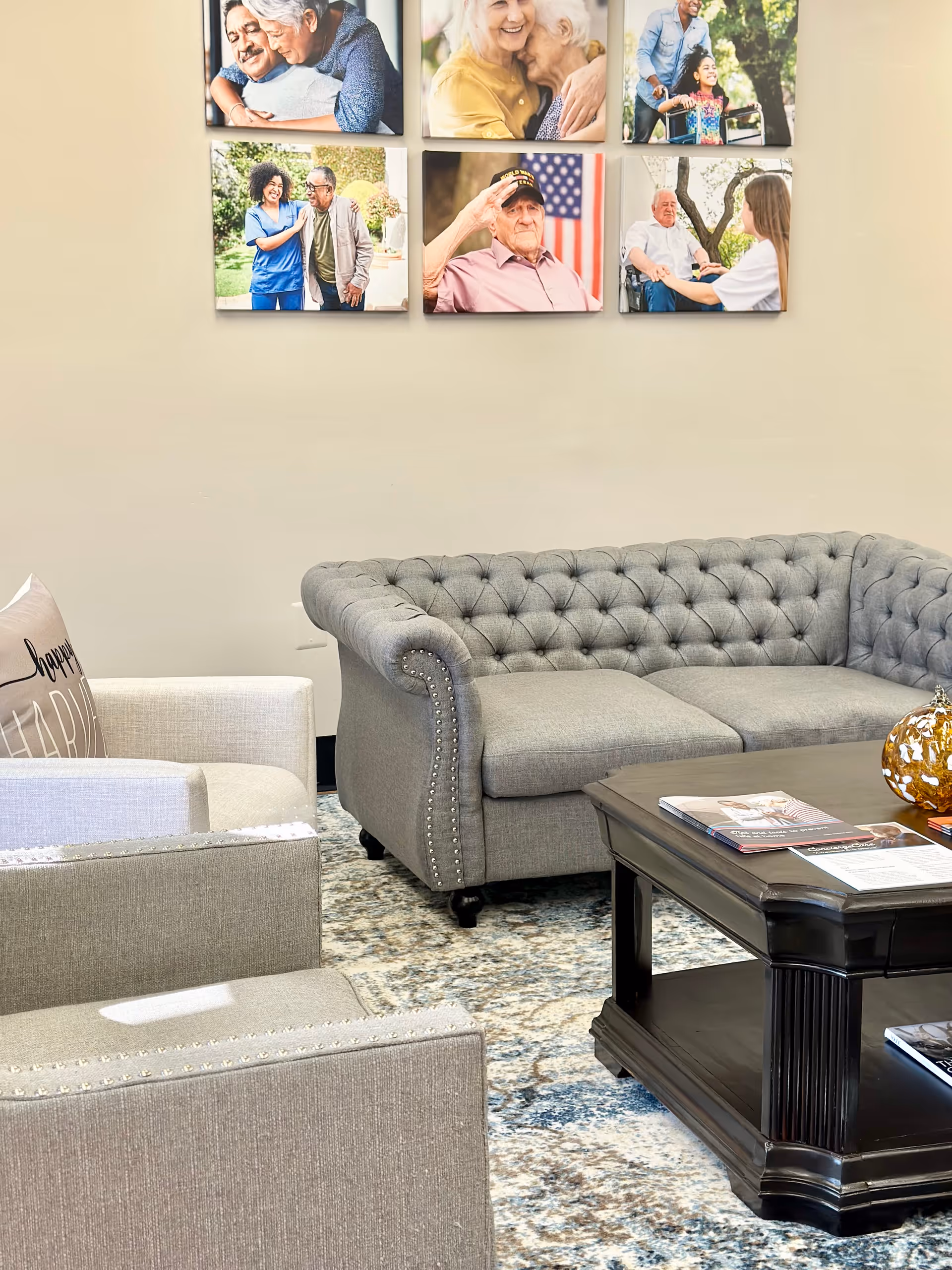 Grey tufted sofa and chairs arranged around a coffee table beneath wall photo panels.
