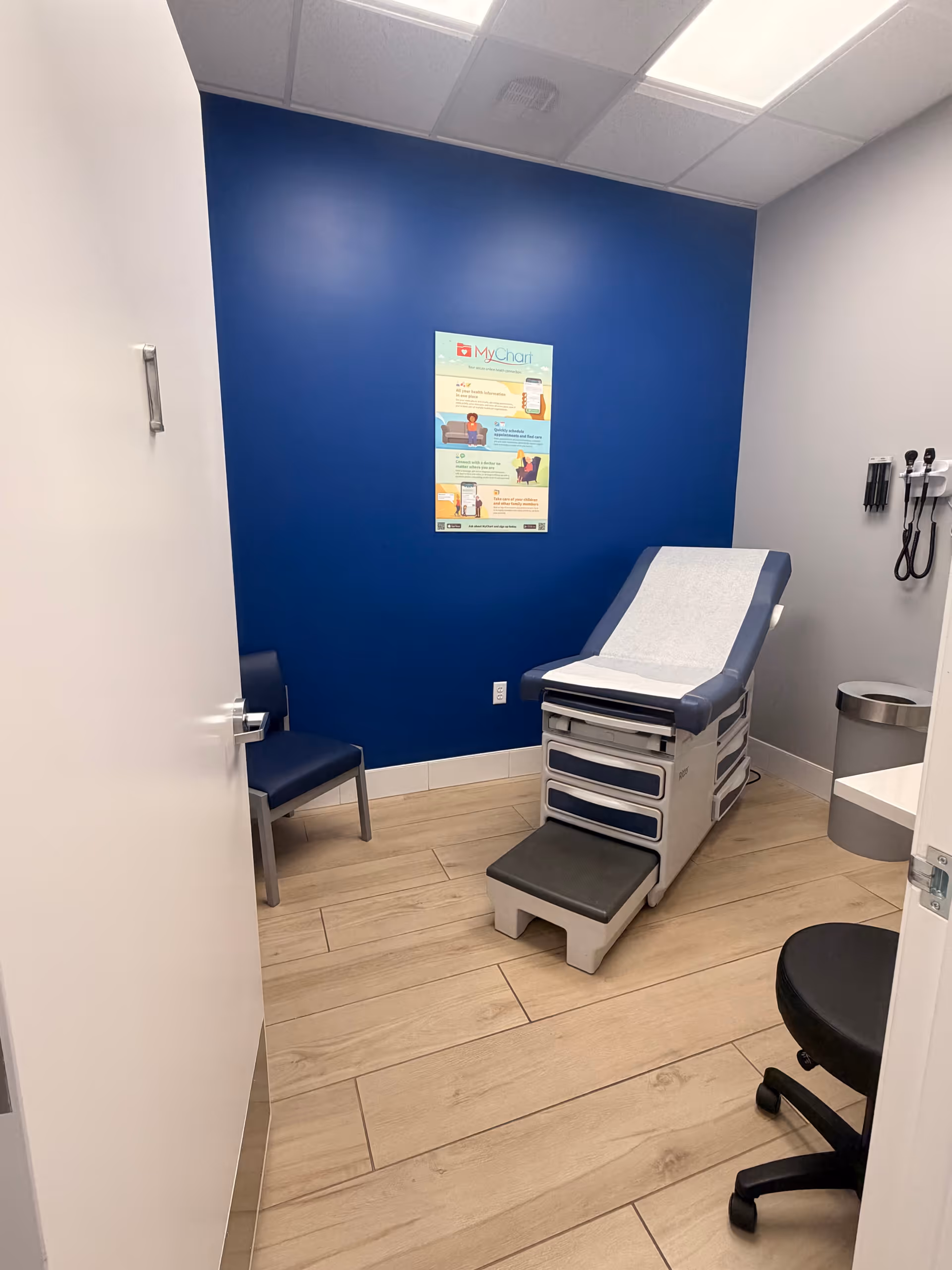 Examination room in a senior facility with blue wall, medical chair, and chart poster.