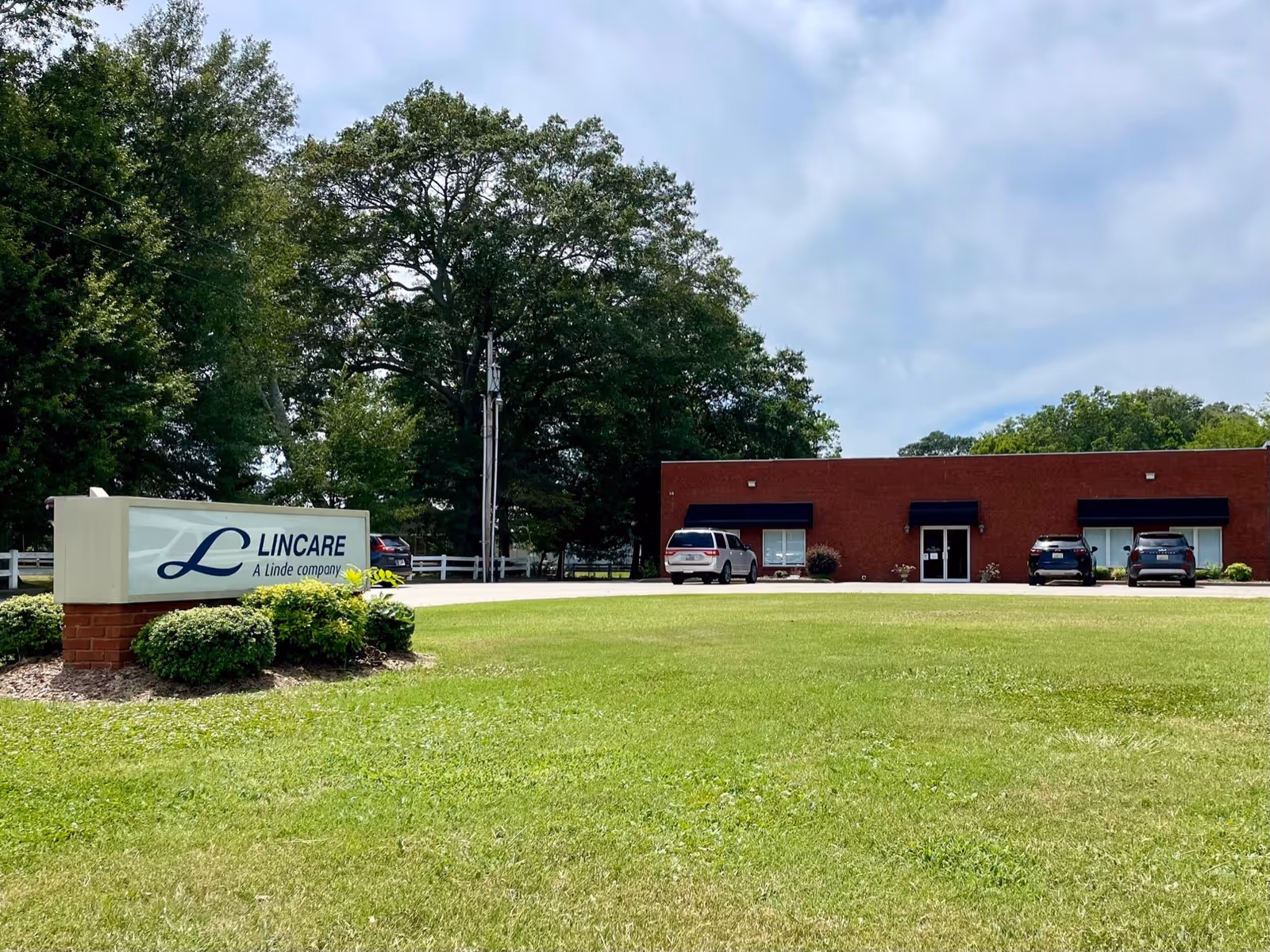 LINCARE sign in front of a brick building with a parking lot and trees.