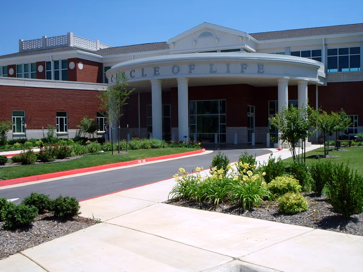 Exterior view of Circle of Life senior living facility entrance with landscaping.