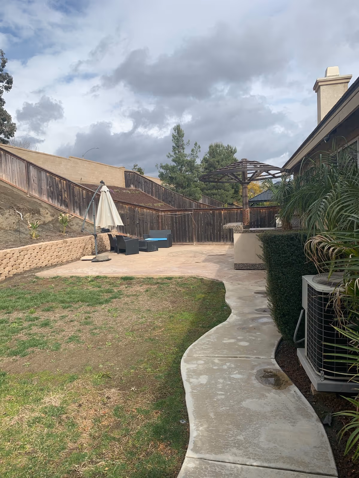 Outdoor patio with seating, umbrella, and plants beside a beige building.