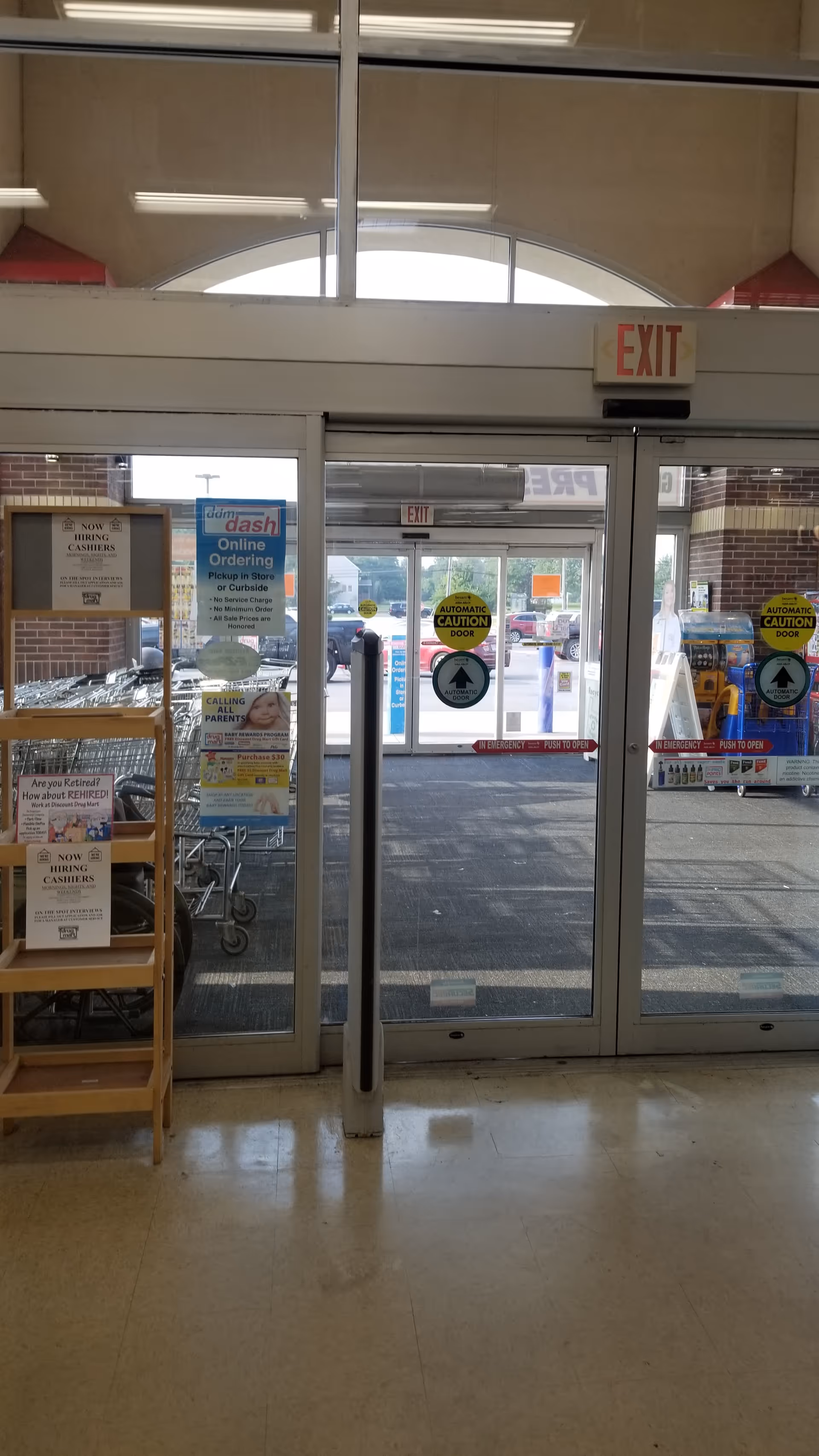 Inside Discount Drug Mart, glass exit doors lead to a front area with posters.
