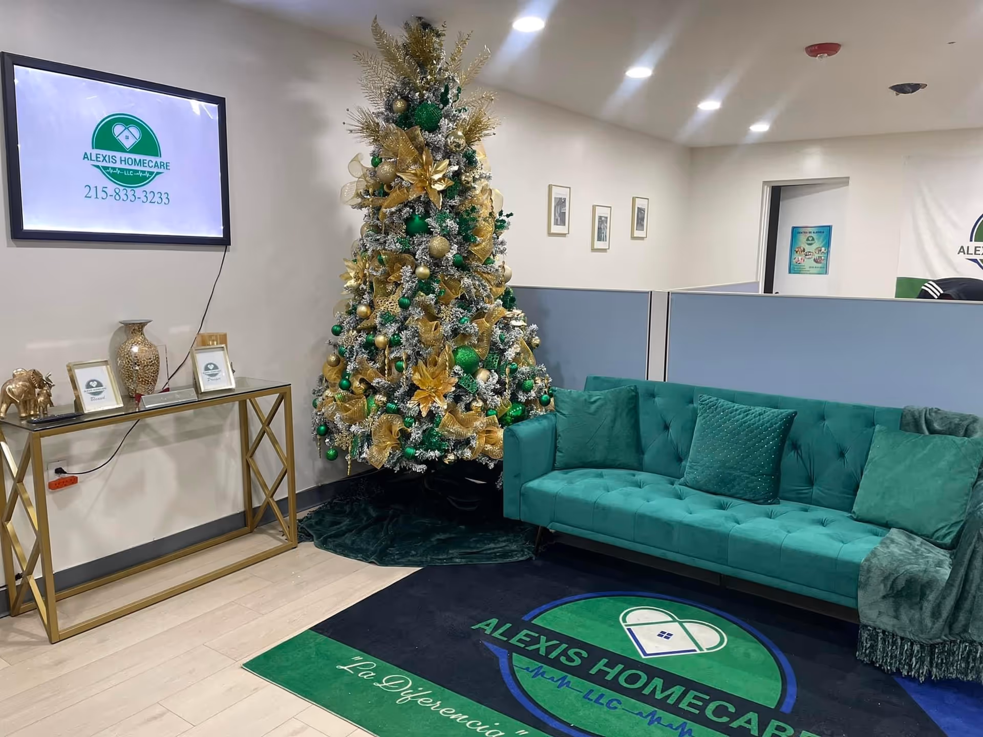 A teal sofa beside a festive Christmas tree in a modern Alexis Homecare lobby.