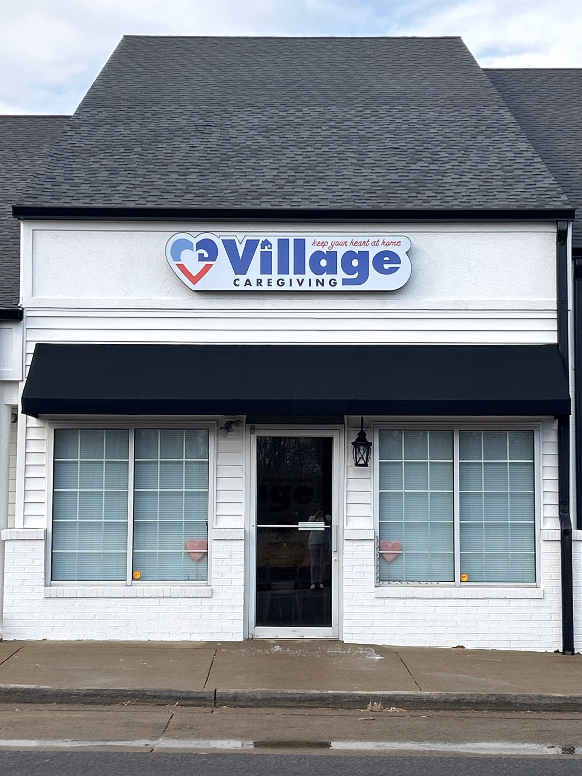 Front view of Village Caregiving building with sign, windows, and entrance door.