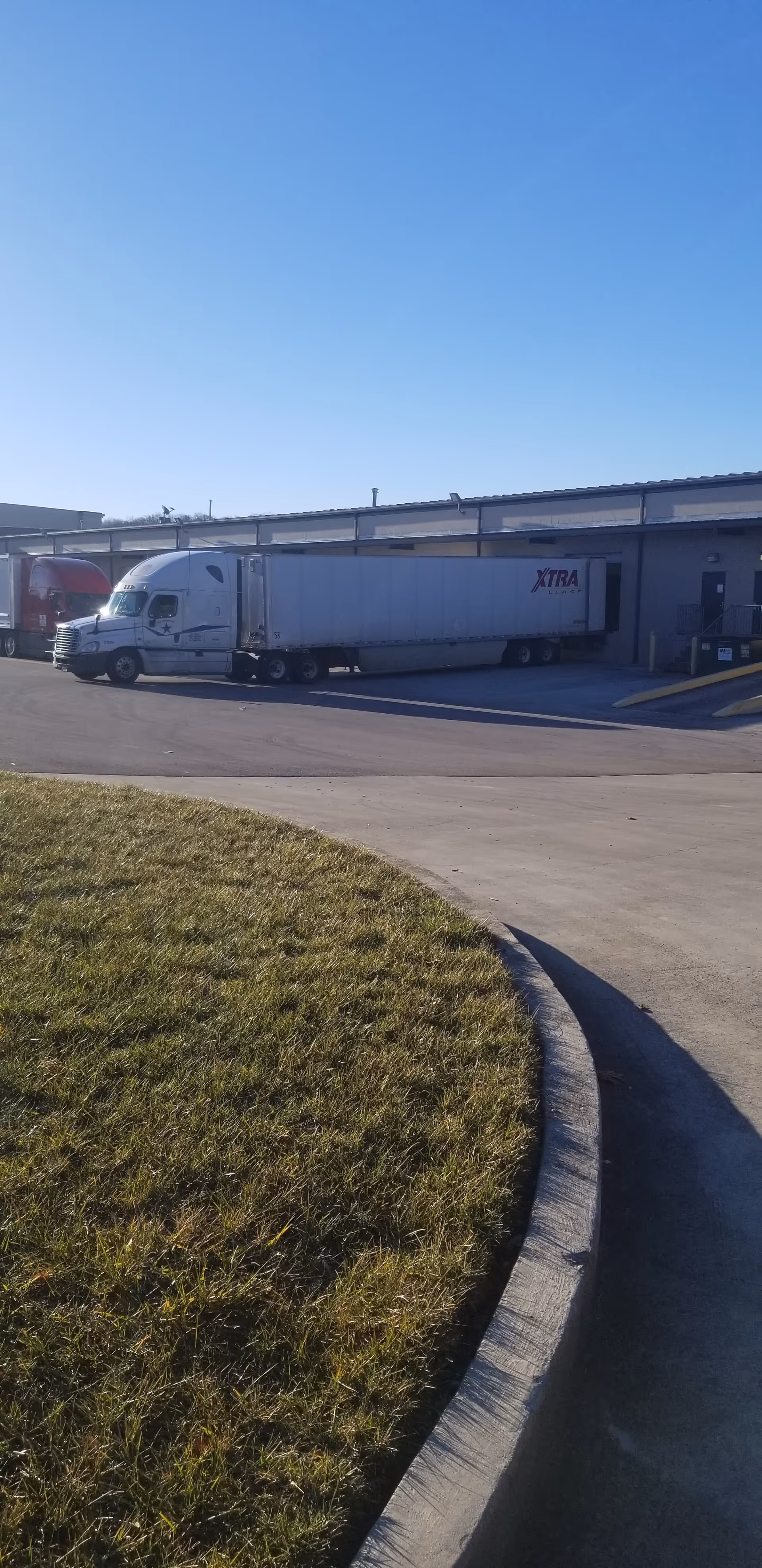Exterior view of a facility loading area with a large white tractor-trailer.