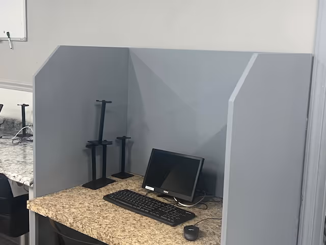 A computer workstation inside a small cubicle with monitor, keyboard, and mouse.