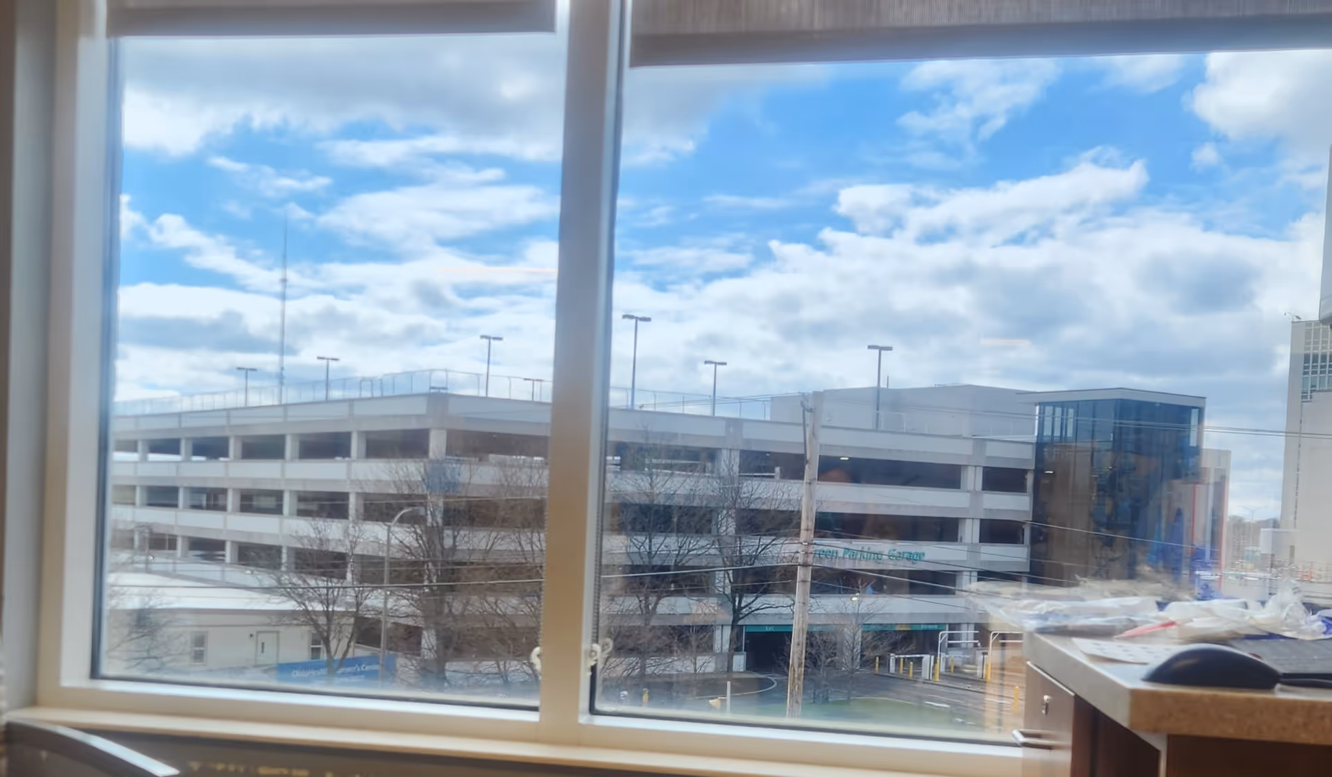Interior view from a facility window showing a parking garage outside.