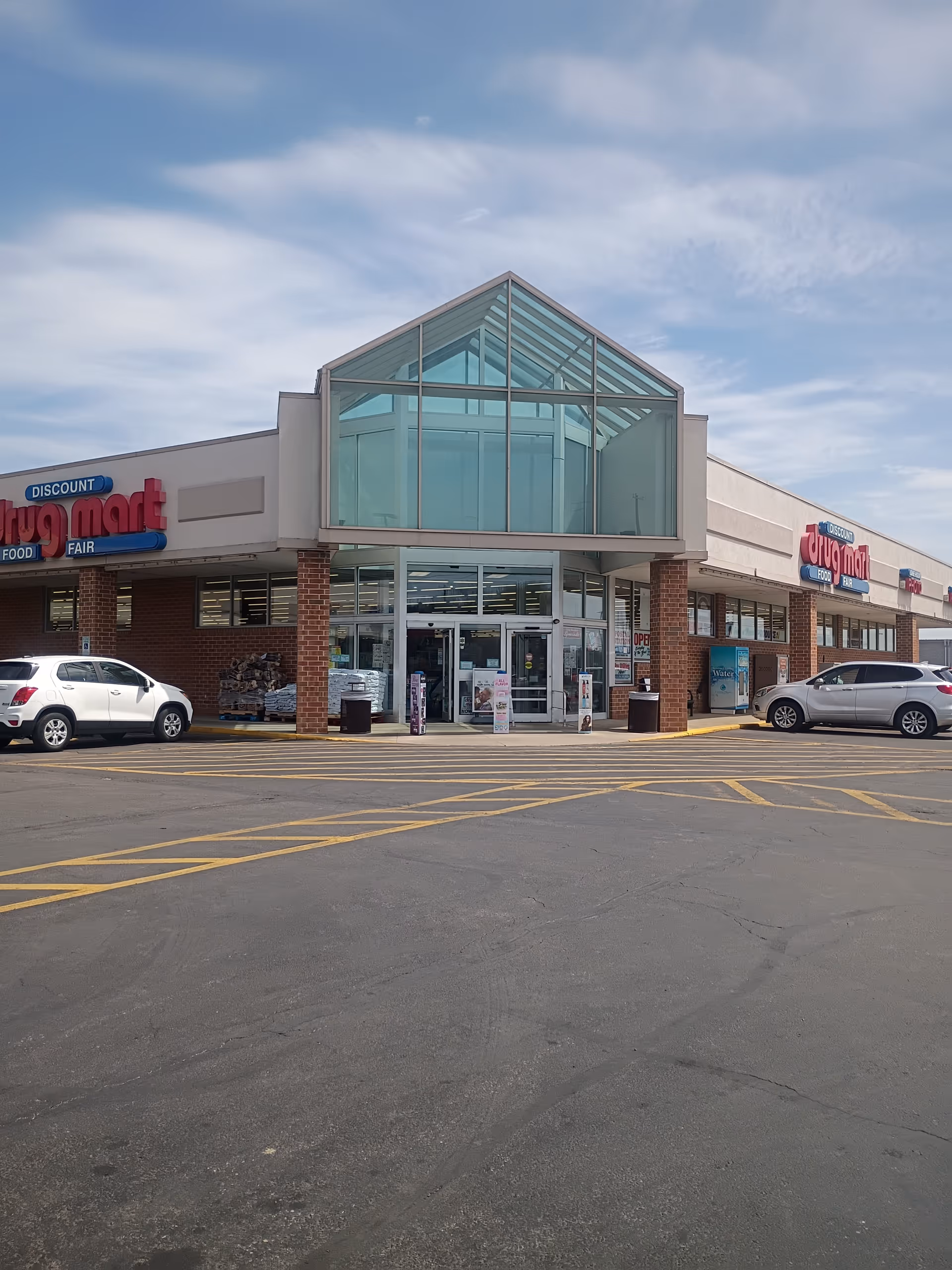Front view of Discount Drug Mart storefront with glass entrance and parking lot.