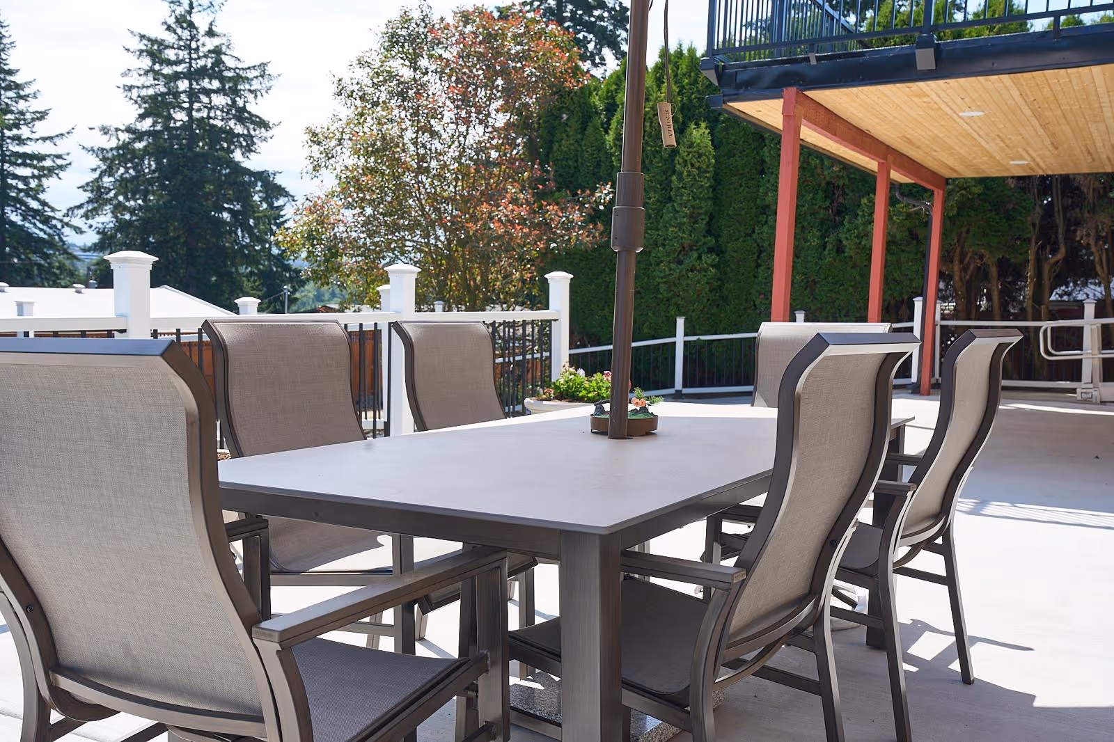 Outdoor dining terrace with a large table and multiple chairs under a shaded area.