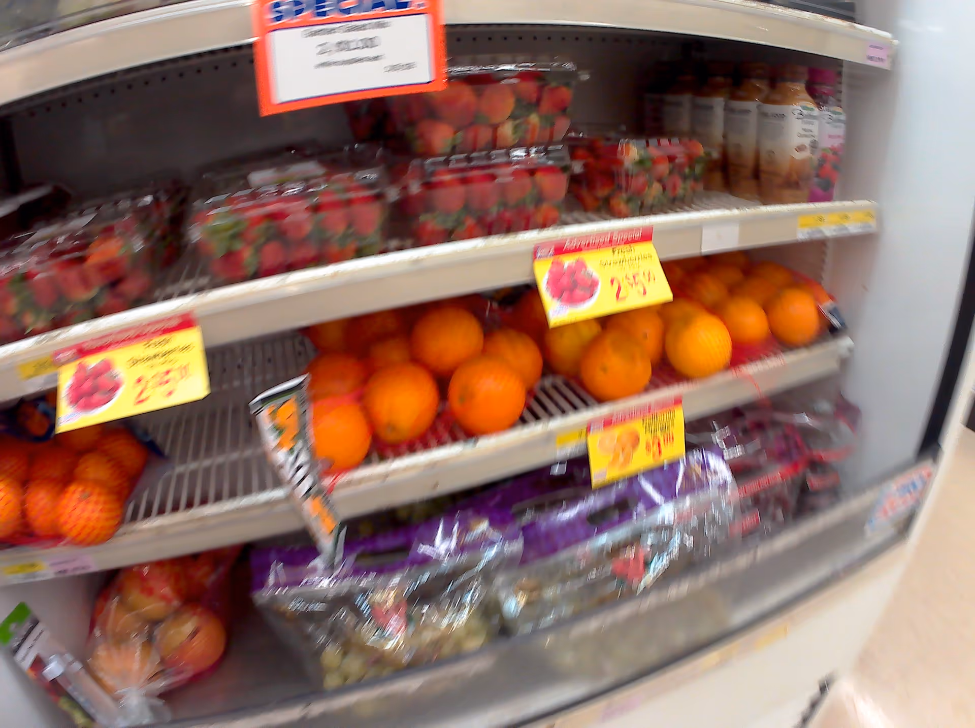 Blurred grocery produce shelves with strawberries and oranges inside a Discount Drug Mart store