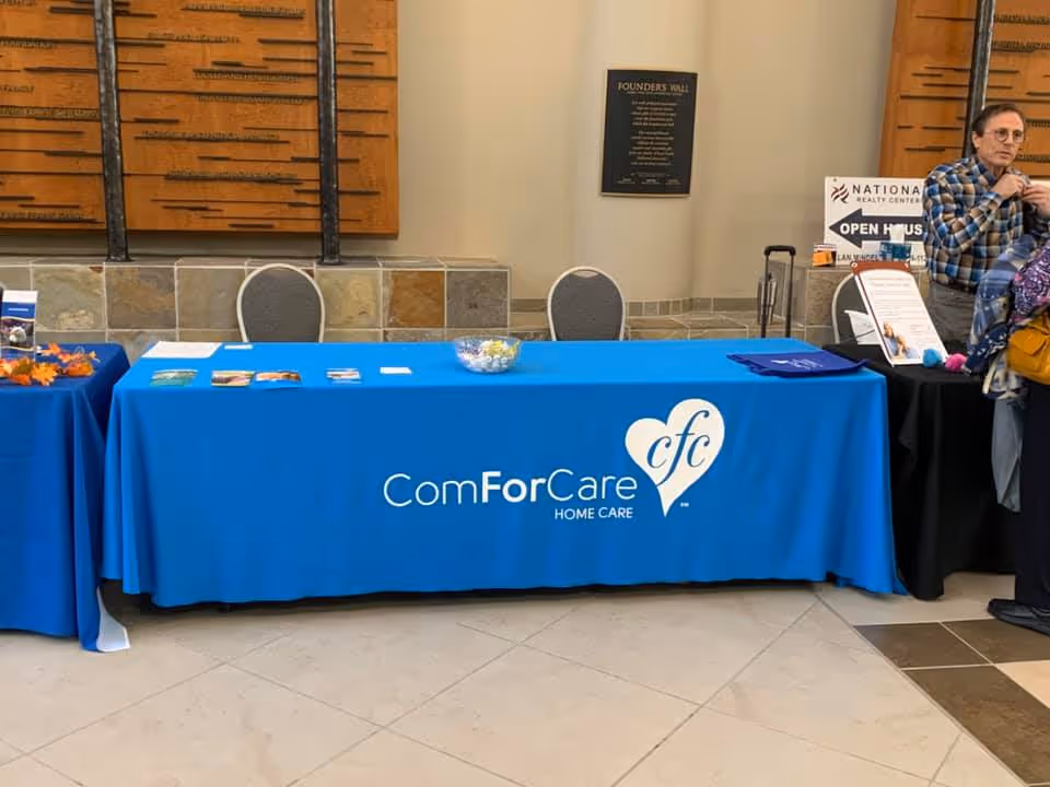Blue ComForCare tablecloth in a lobby, with brochures and a person nearby.