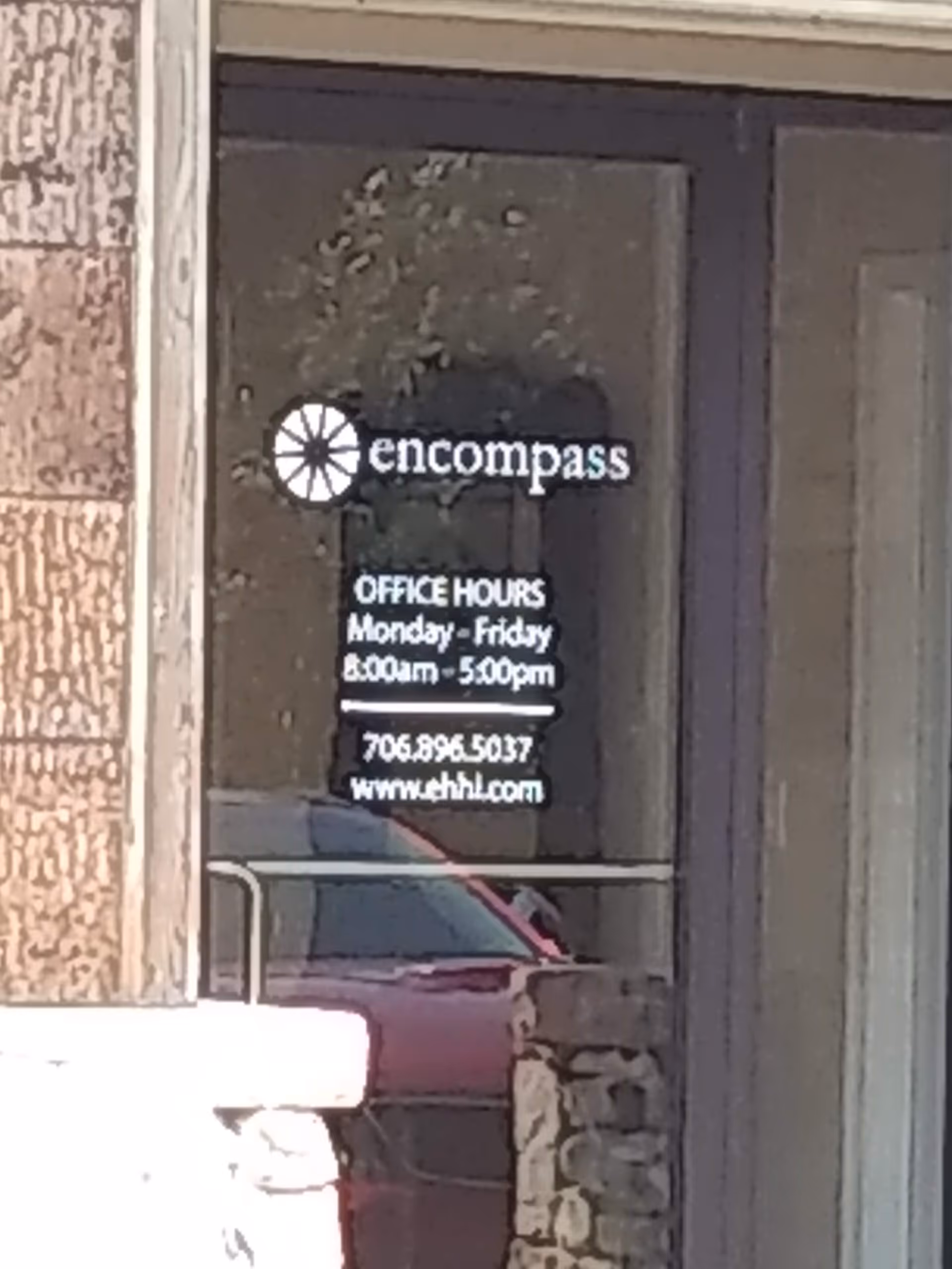 Glass entrance door displays Encompass logo and office hours.