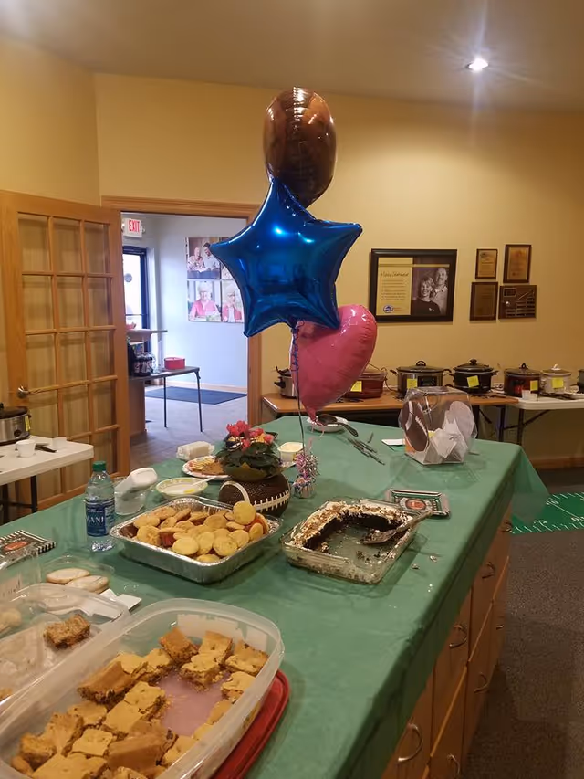 Buffet table with snacks and balloons in a senior living dining area.