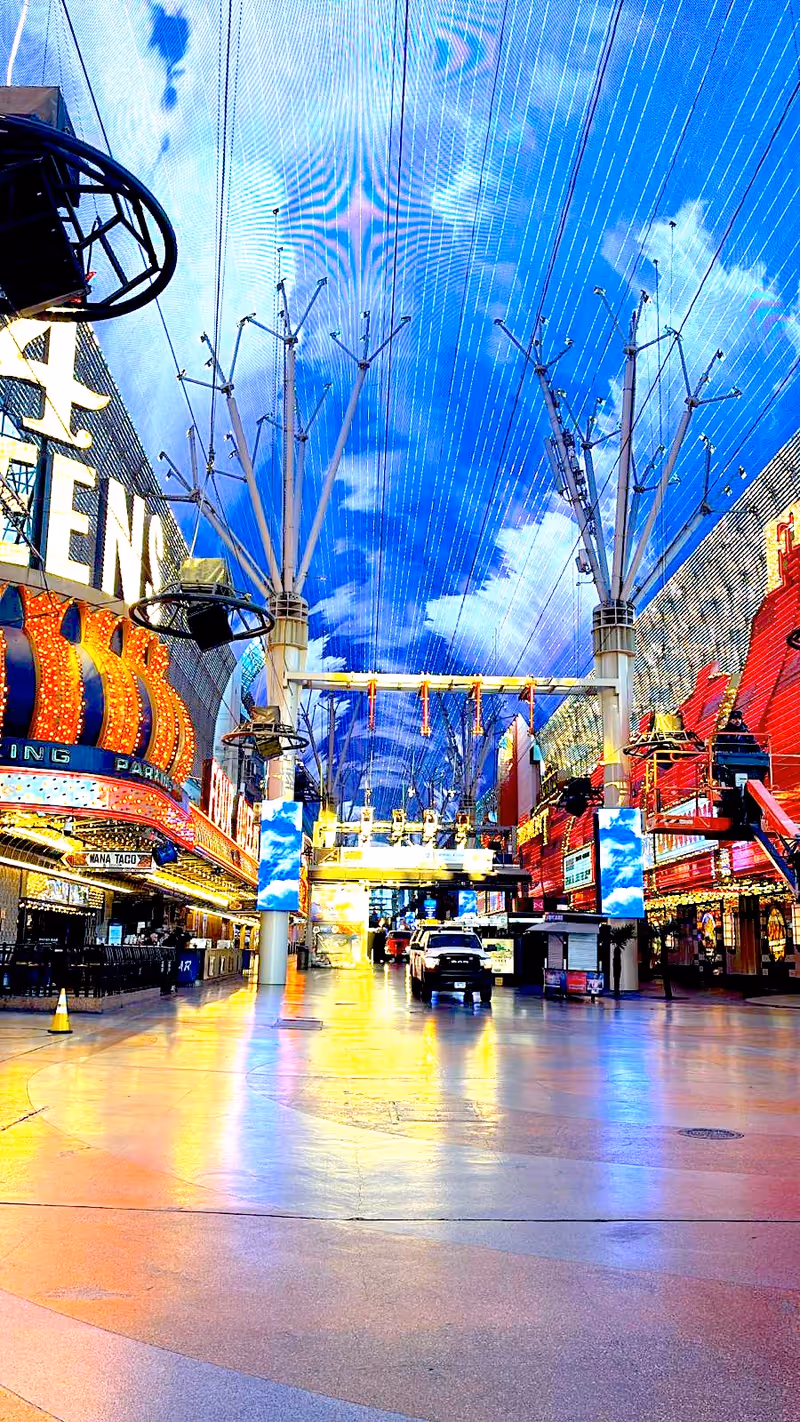 Indoor arcade-like street with neon signs and a blue skylight canopy.