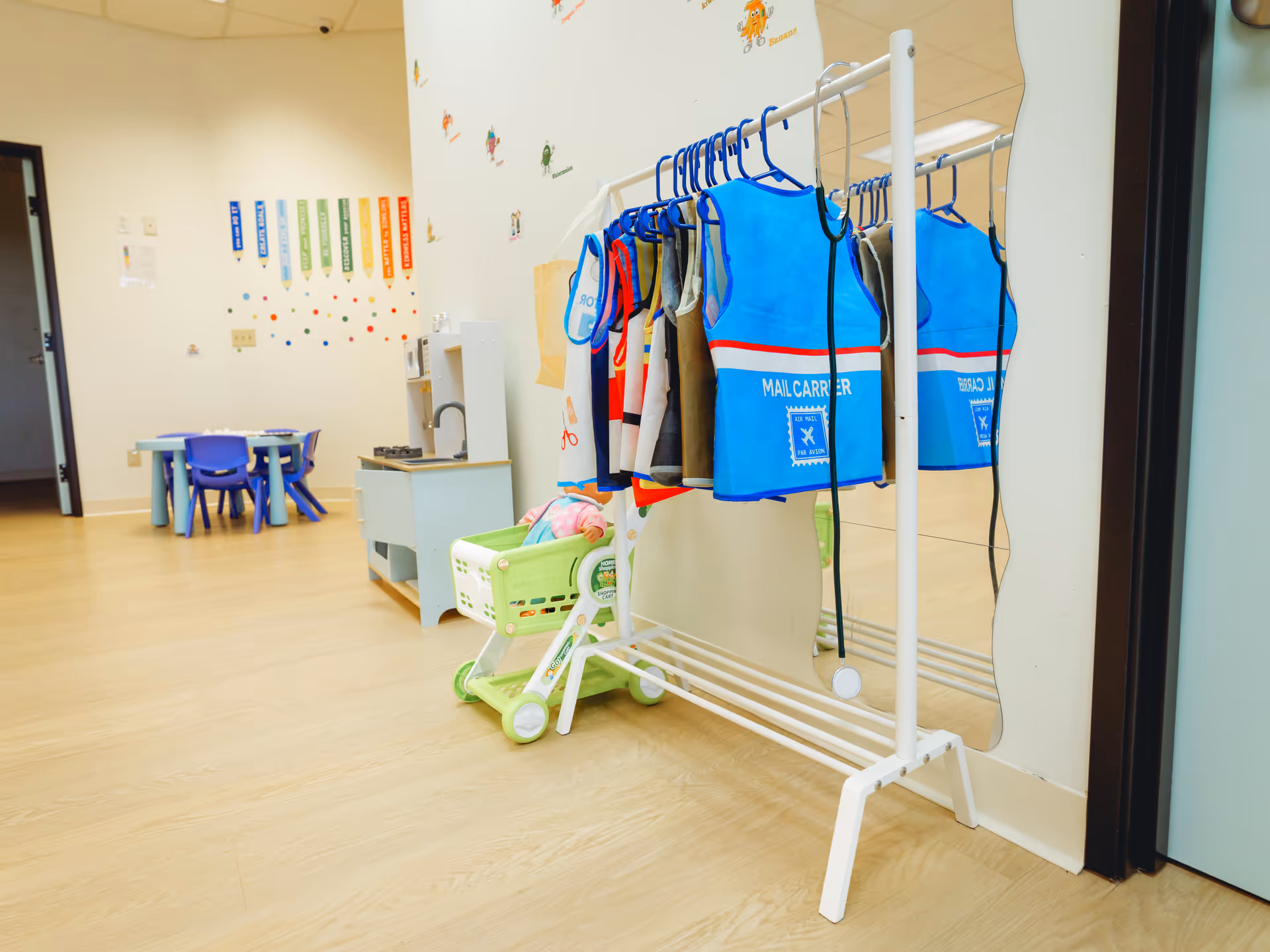 Interior therapy room with blue vests on a rack and children's furniture nearby.