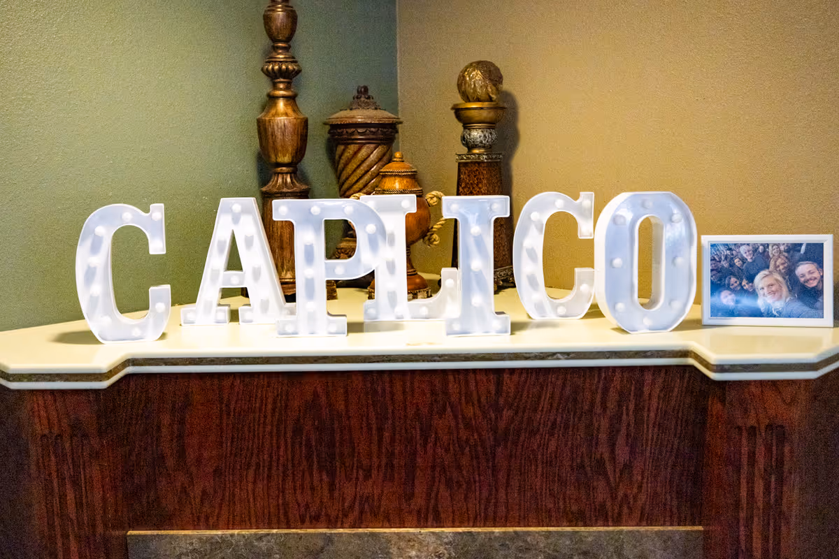 Illuminated marquee letters spell CAPITCO on a reception counter with a photo frame.