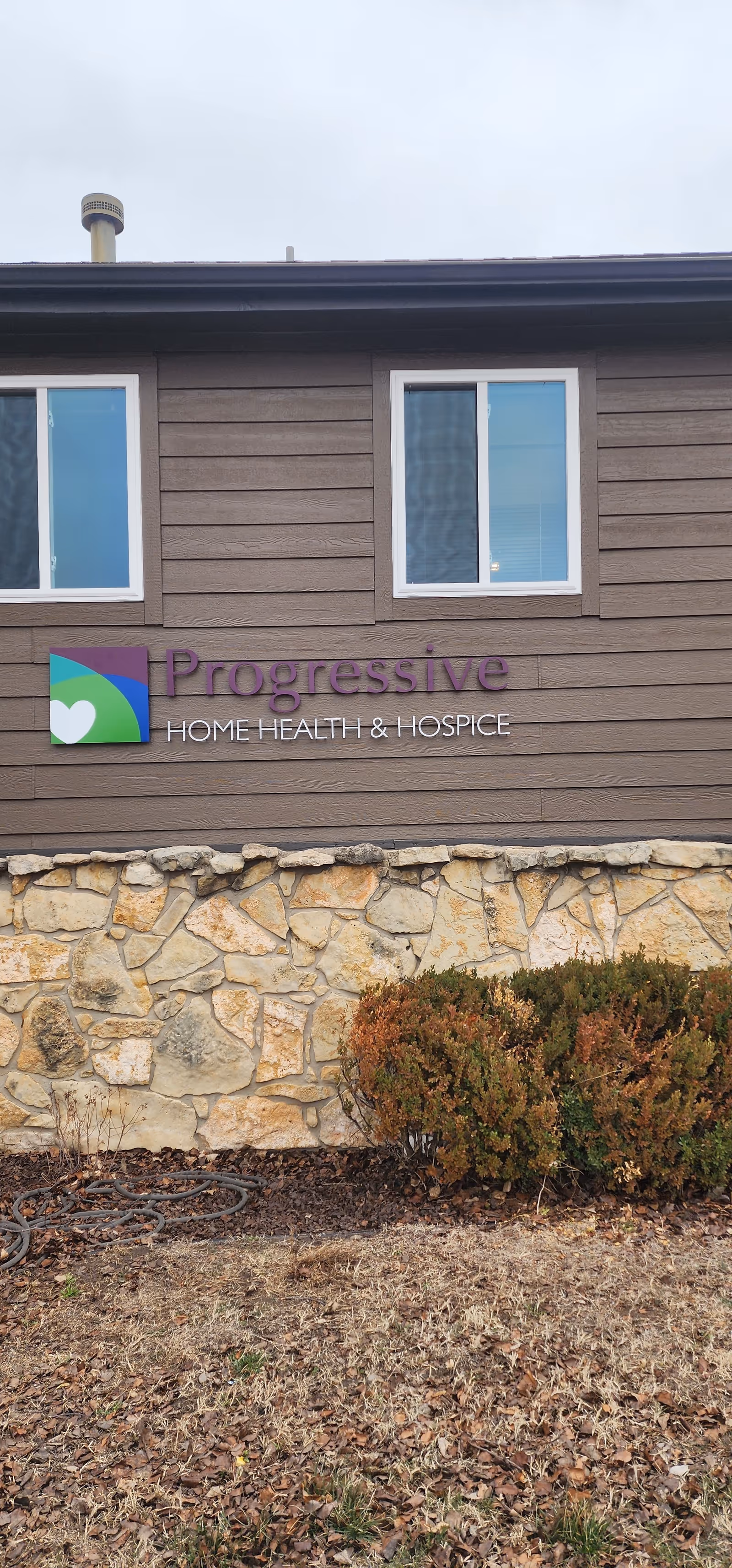 Exterior view of a Progressive Home Health & Hospice building with a stone foundation.