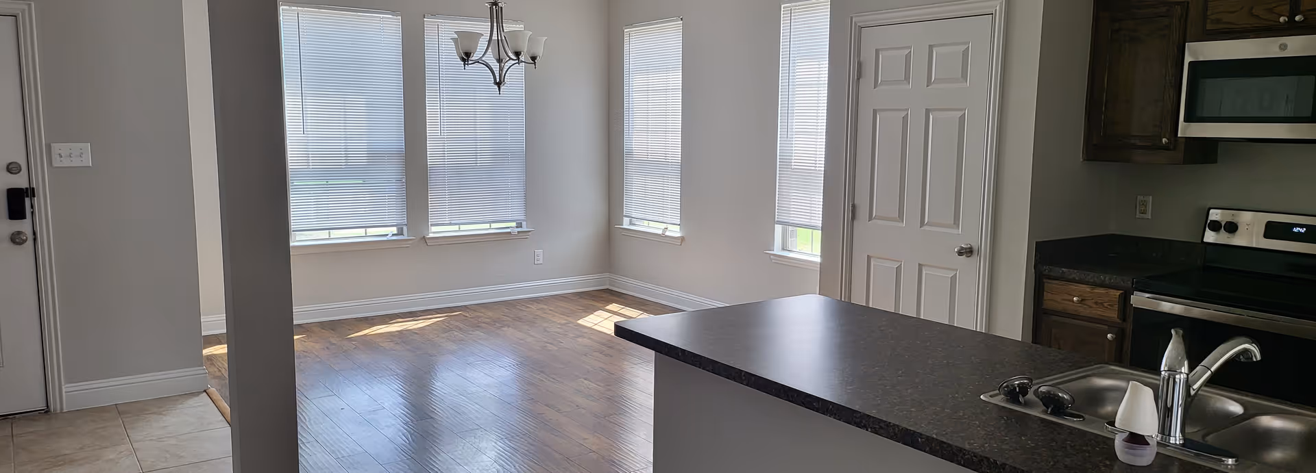 Bright kitchen with island, sink, and adjacent dining area by windows in a senior living unit.