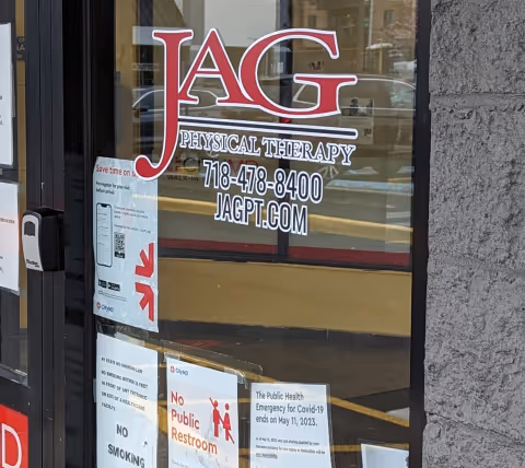 Glass storefront door for JAG Physical Therapy with logo and posted notices.