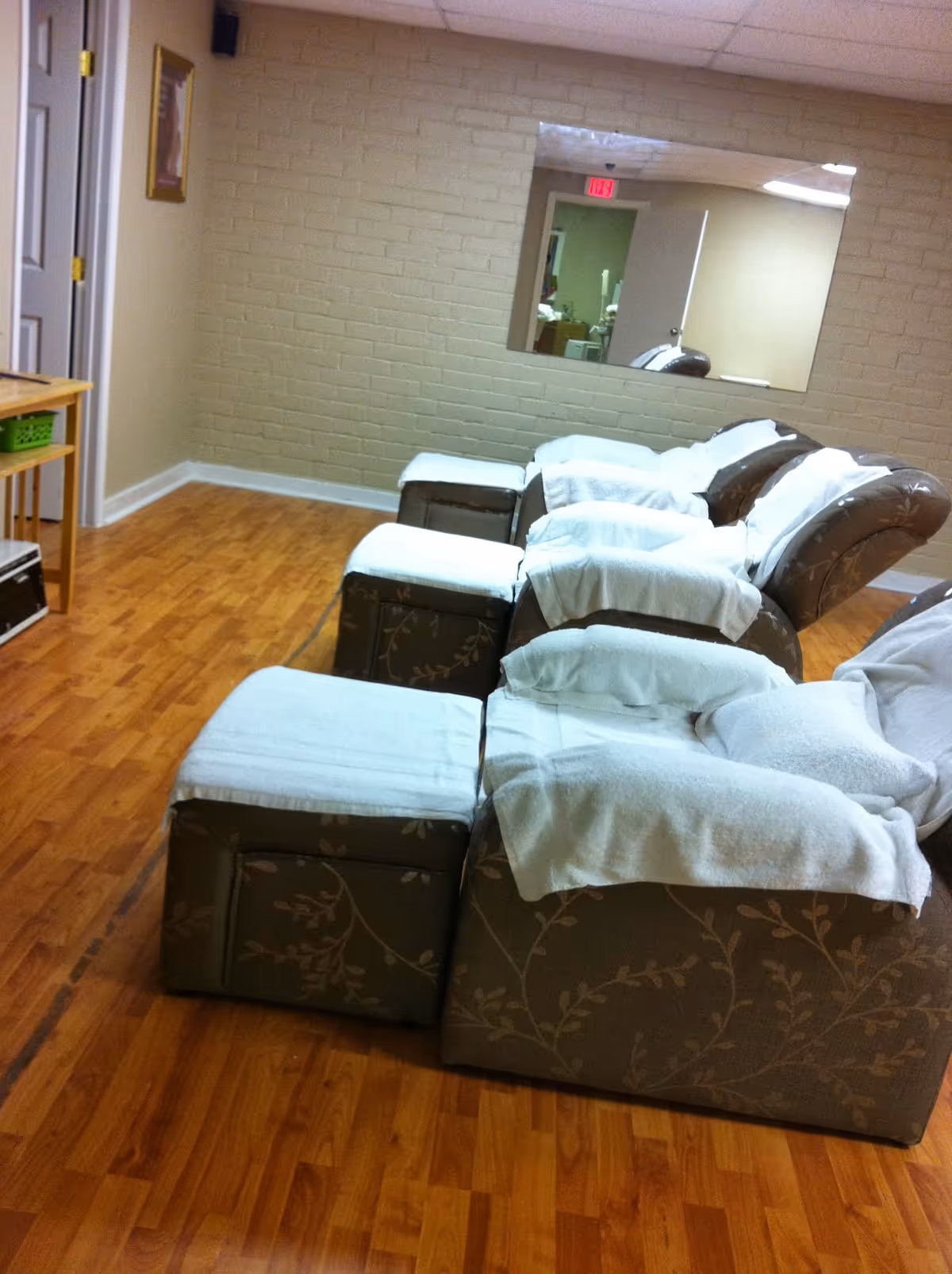 Row of brown patterned recliners with white towels in a treatment room.